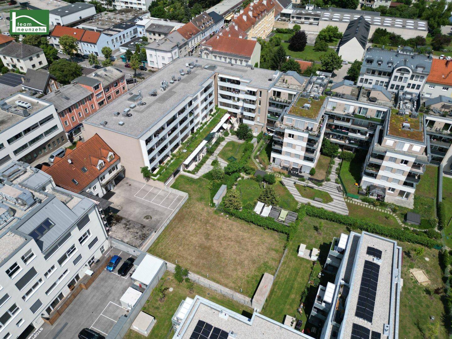 Schrägansicht einer modernen Wohnanlage mit weitläufigen Grünflächen und angrenzenden Gebäuden.