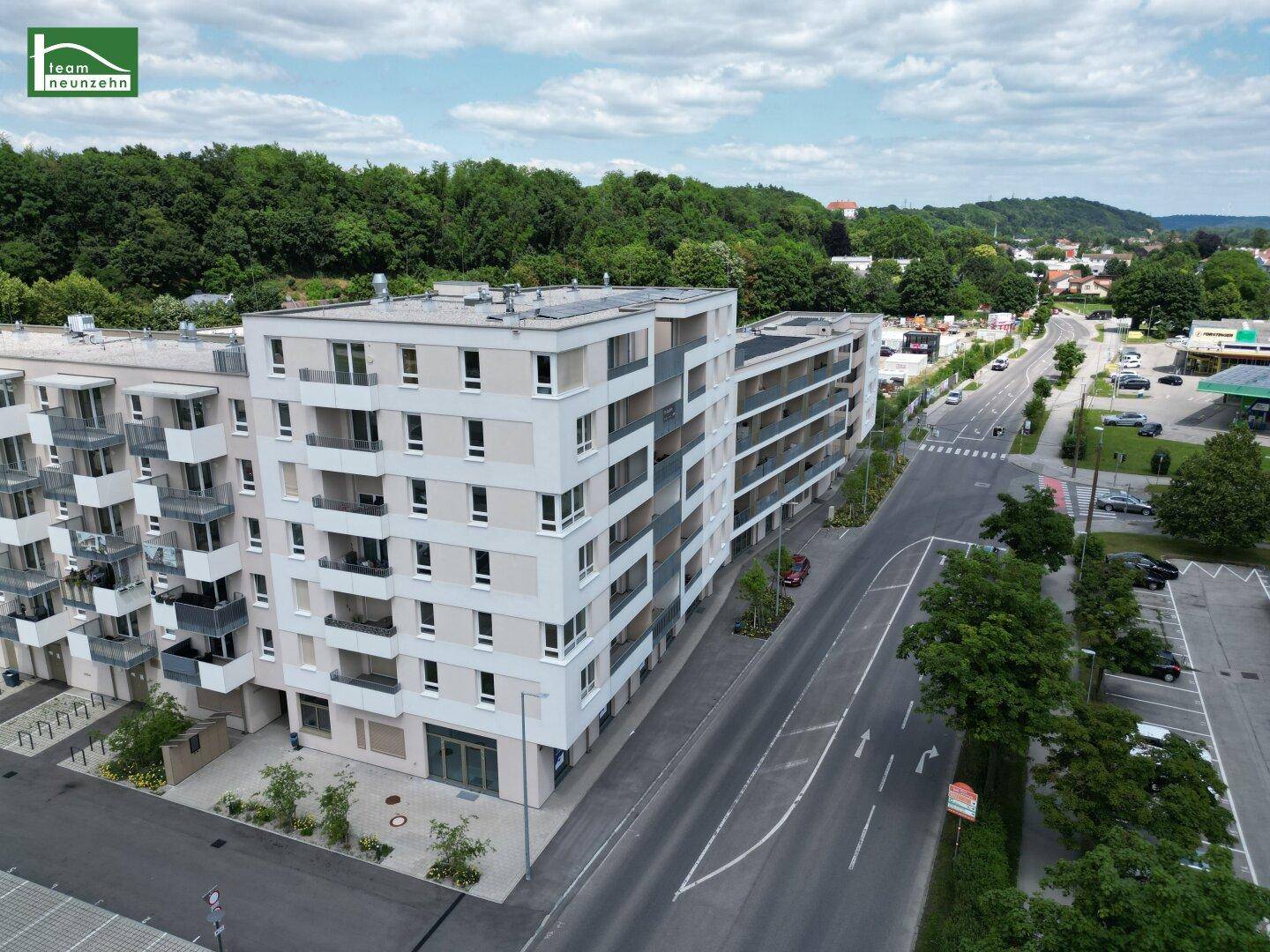 Luftaufnahme des modernen Wohngebäudes entlang einer Straße mit umliegender Bebauung.