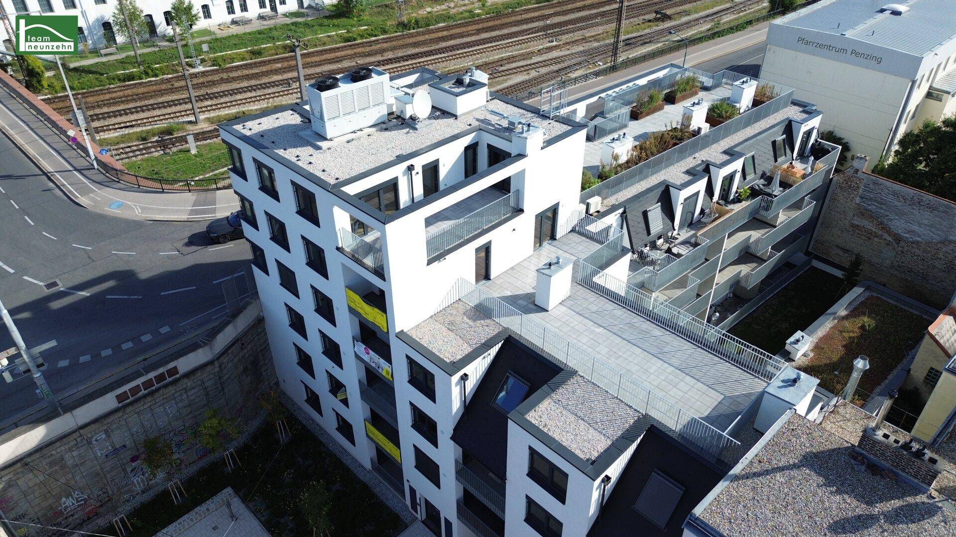 Luftaufnahme des modernen Wohnkomplexes mit Flachdach und Terrassen in urbaner Umgebung.