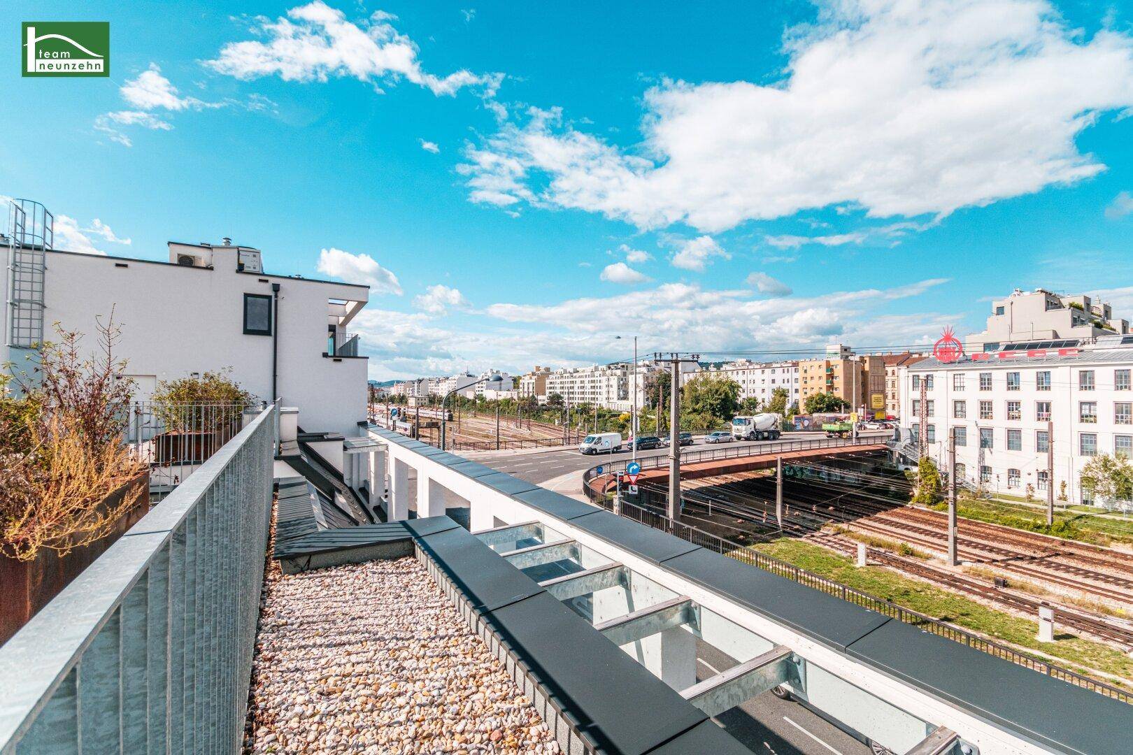 Dachterrasse mit Kiesboden und Blick auf die Stadt und die umliegende Infrastruktur.