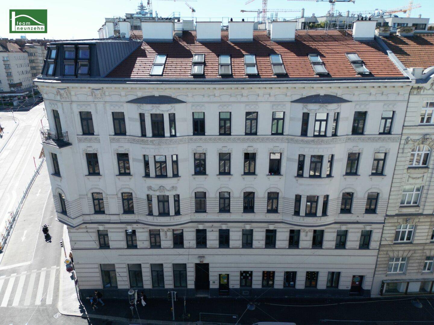 Detailansicht der historischen Fassade eines Eckgebäudes mit vielen Fenstern und Dachausbauten.