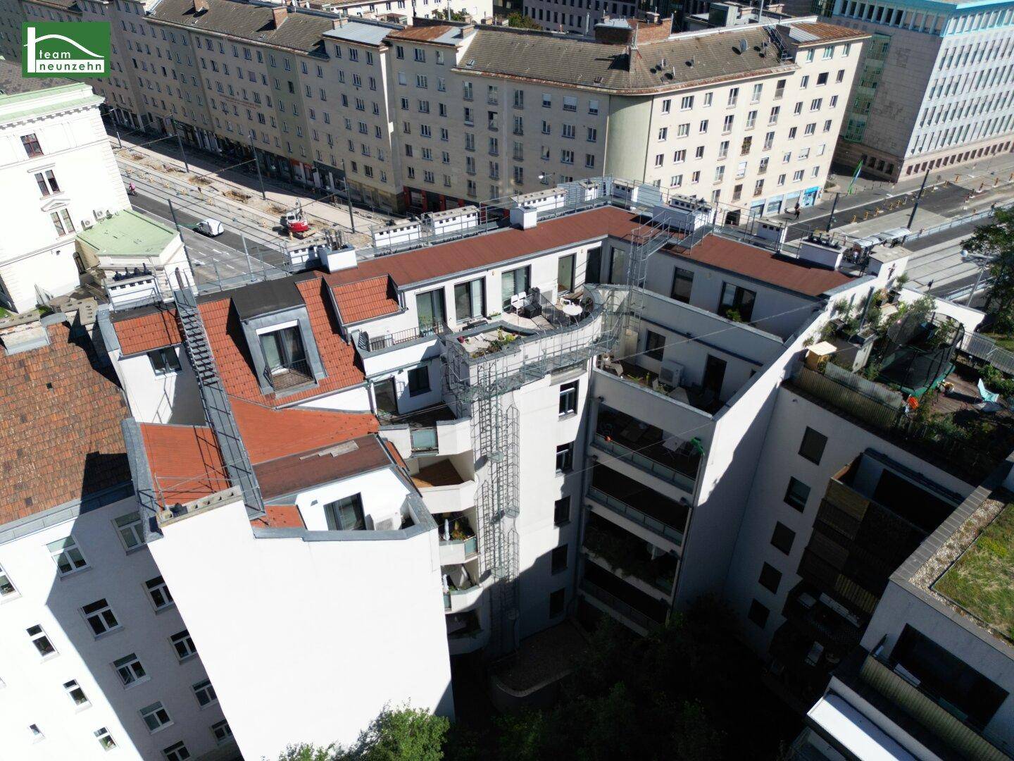 Dachlandschaft eines Wohnkomplexes mit Terrassen, Balkonen und begrünten Innenhöfen.