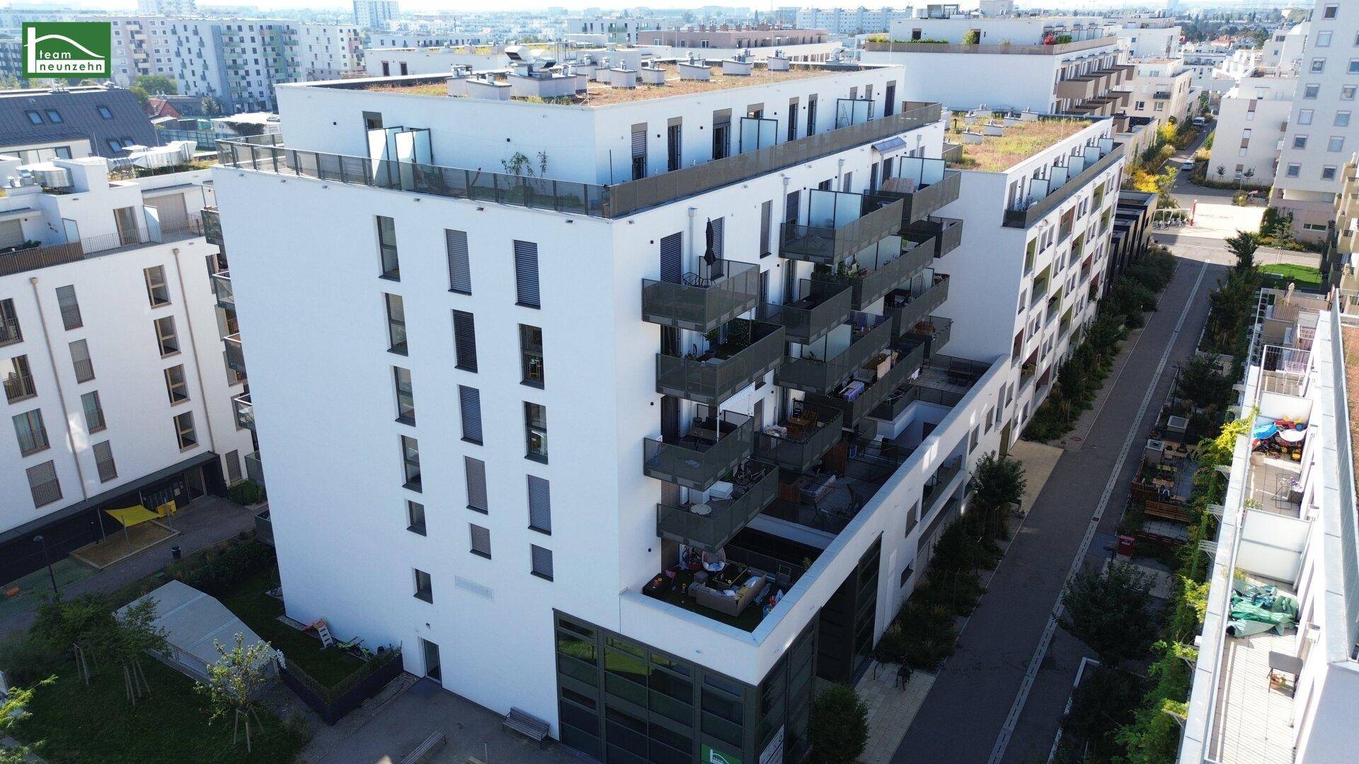 Luftaufnahme eines modernen Wohnkomplexes mit weißen Fassaden und Balkonen in einer städtischen Umgebung.