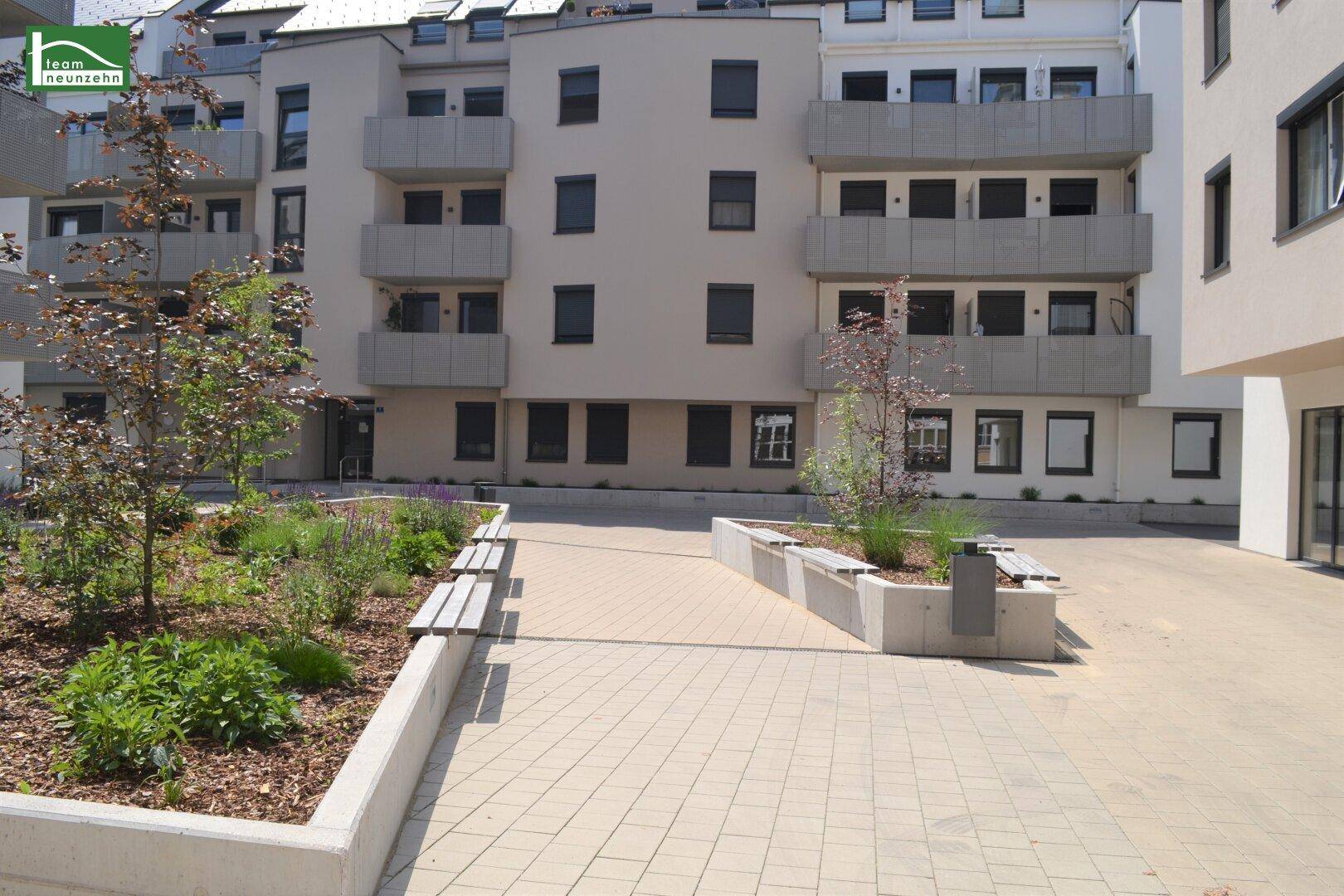 Gepflegter Innenhof mit Sitzgelegenheiten und Grünflächen zwischen modernen Wohngebäuden.