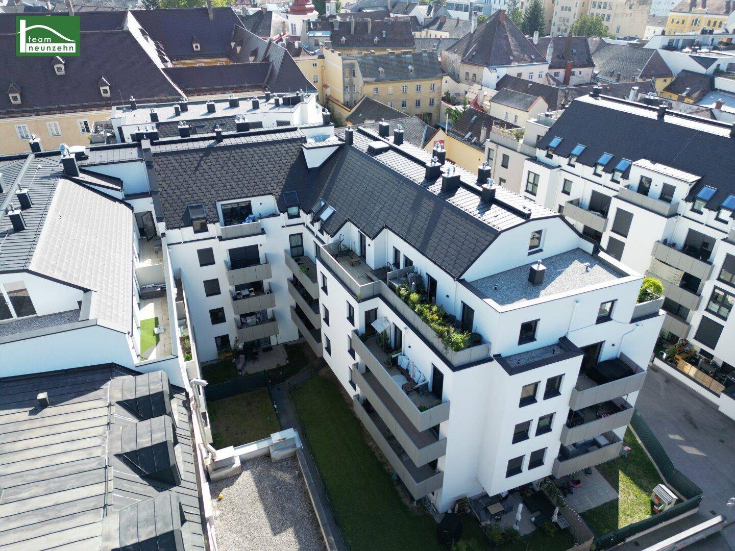 Moderne Wohngebäude mit Flachdächern, Balkonen und begrünten Dachterrassen in der Stadt.