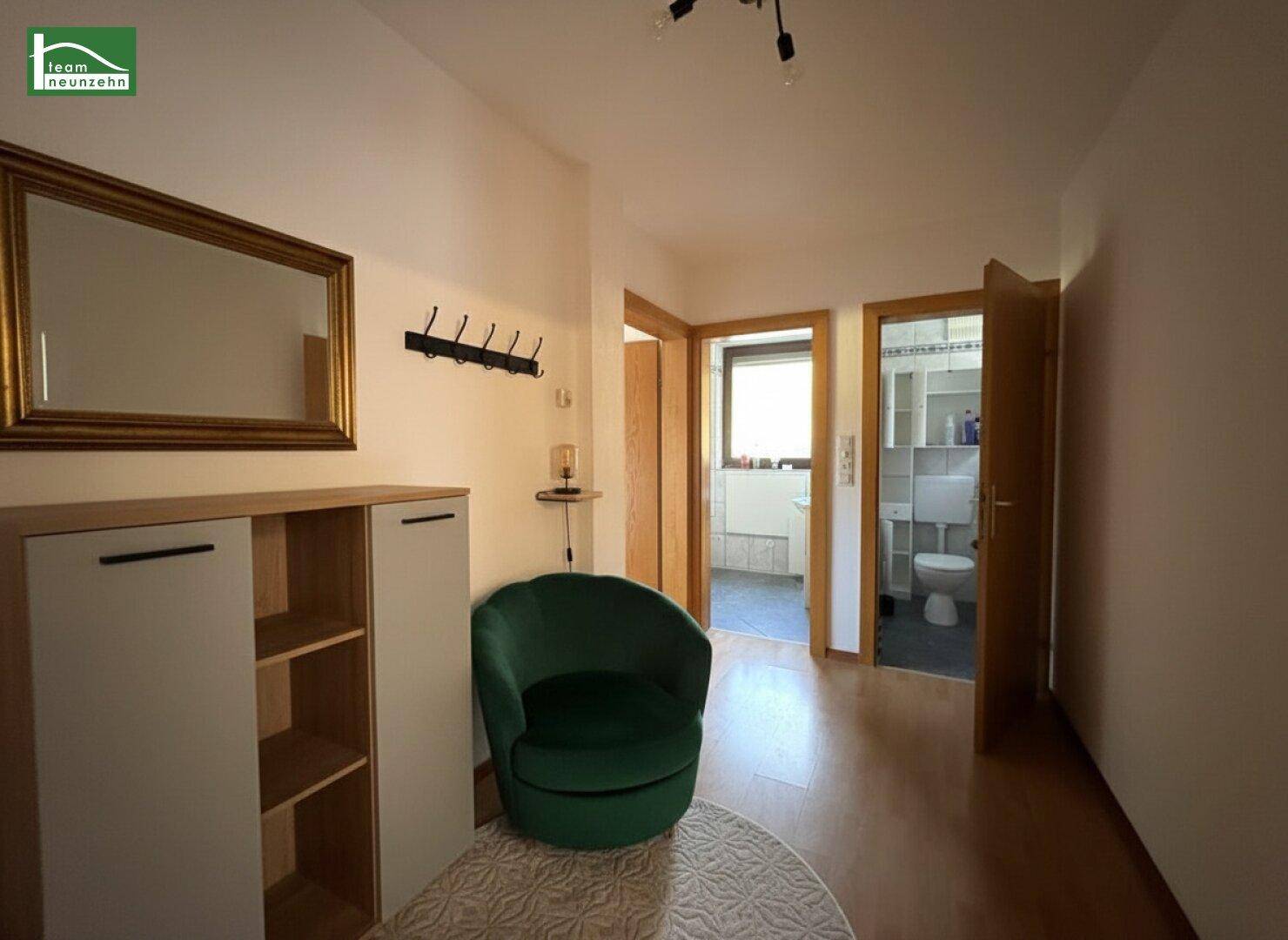 Heller Flur mit Holzboden, Spiegel und Zugang zu Bad und WC.