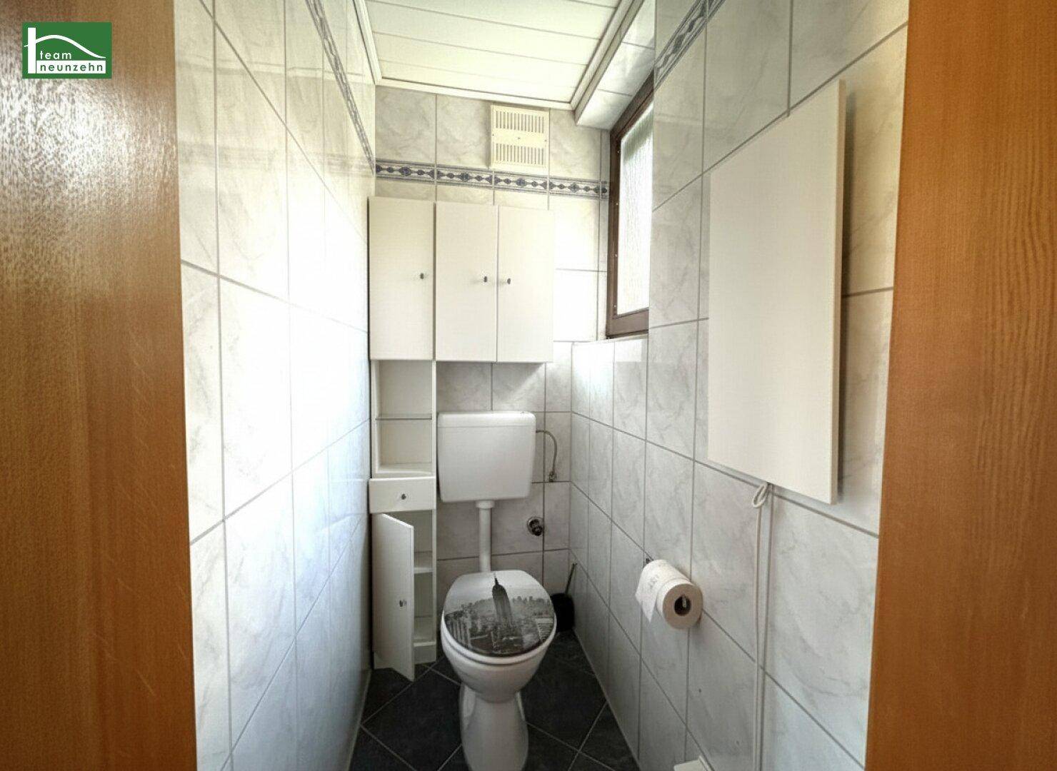 Kleines WC mit Fliesenboden, Toilette und Fenster.