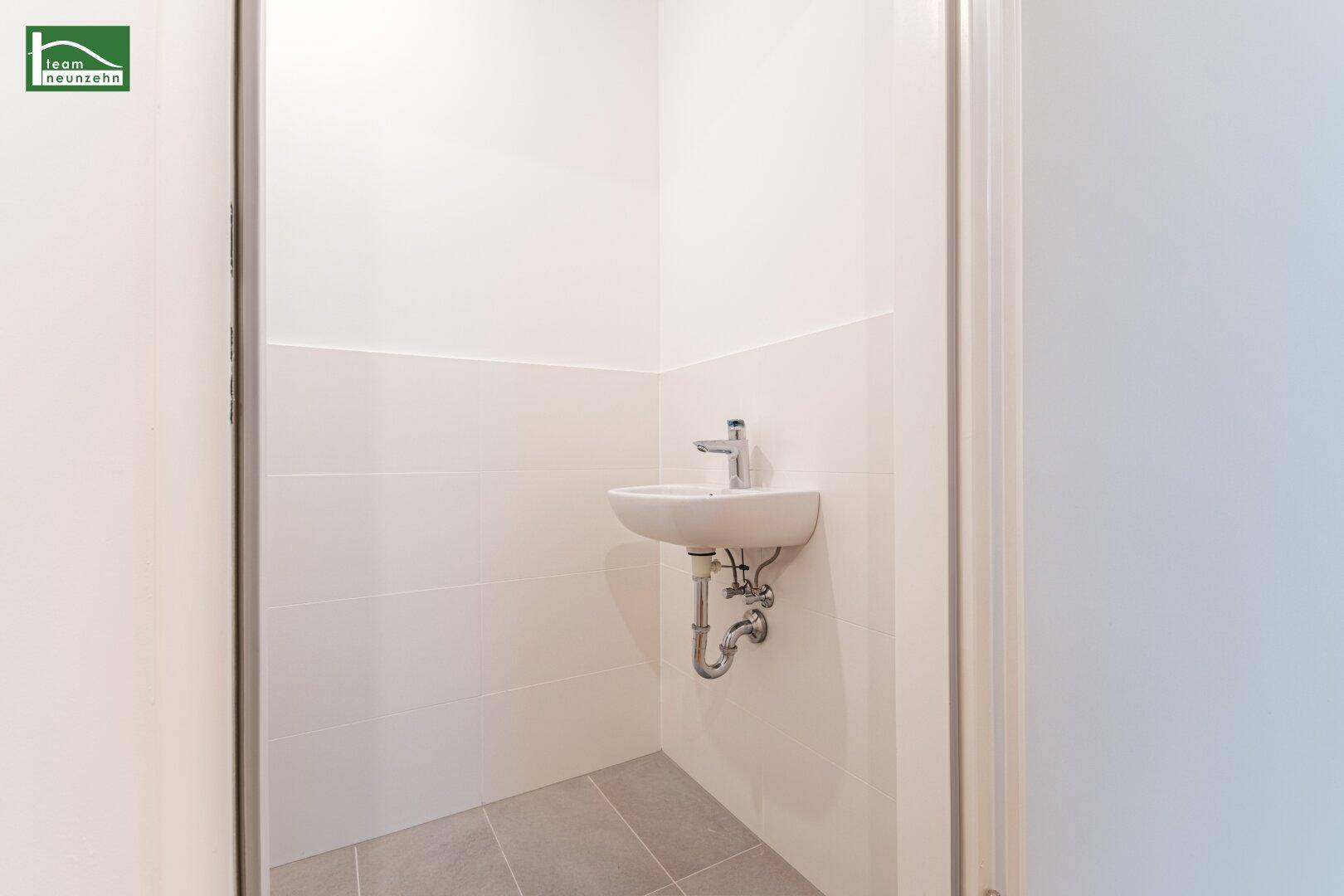 Kleines Waschbecken in einem modernen Gäste-WC oder Badezimmer mit hellen Fliesen.
