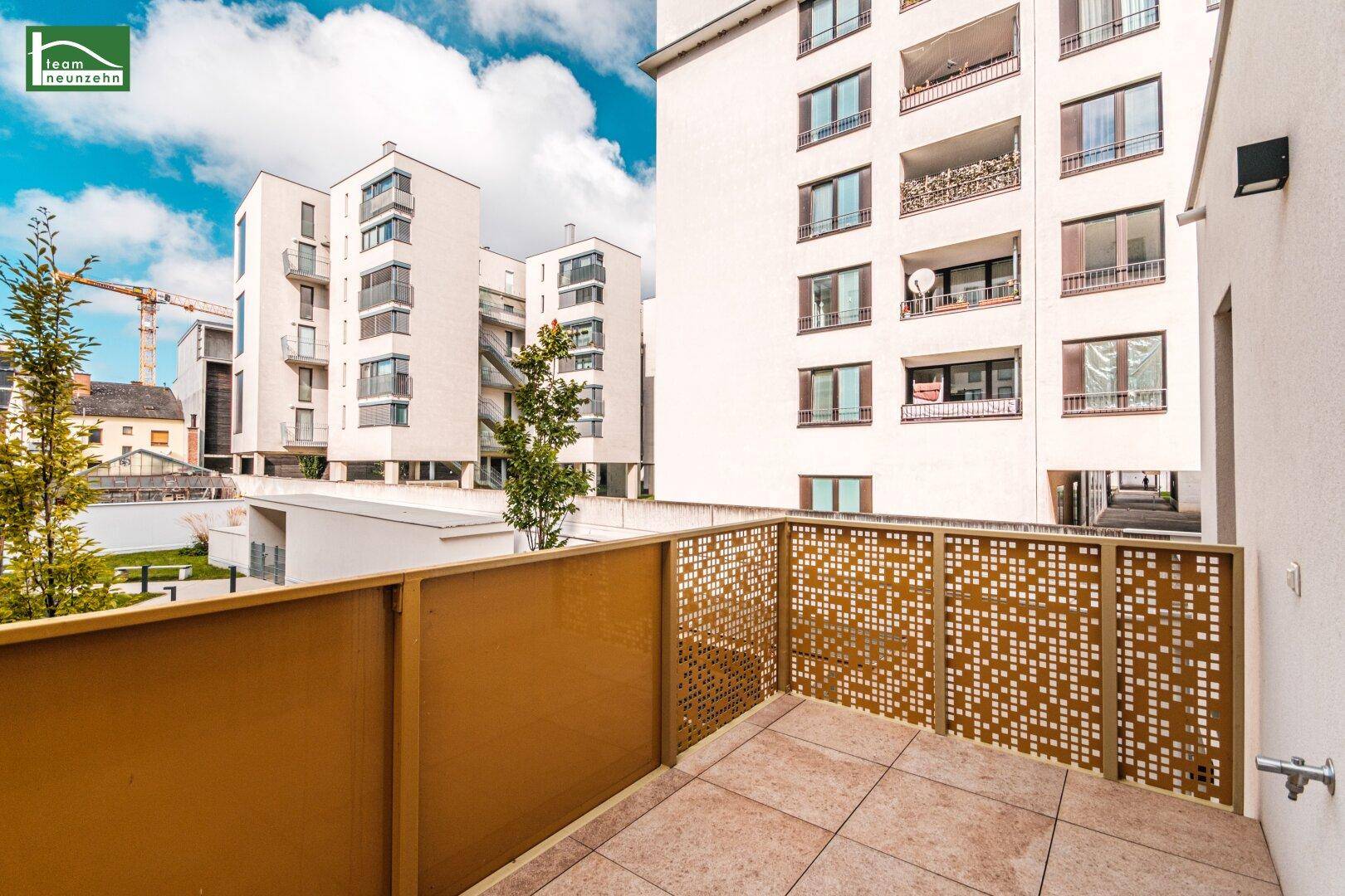 Geräumiger Balkon mit Fliesenboden und Blick auf die umliegenden modernen Gebäude.