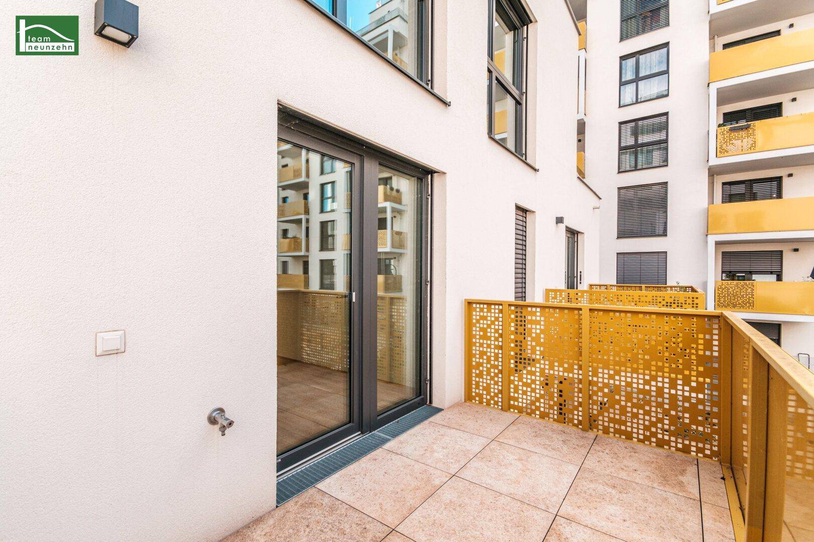 Moderner Balkon mit Fliesenboden und dekorativem Metallgeländer an der Fassade.