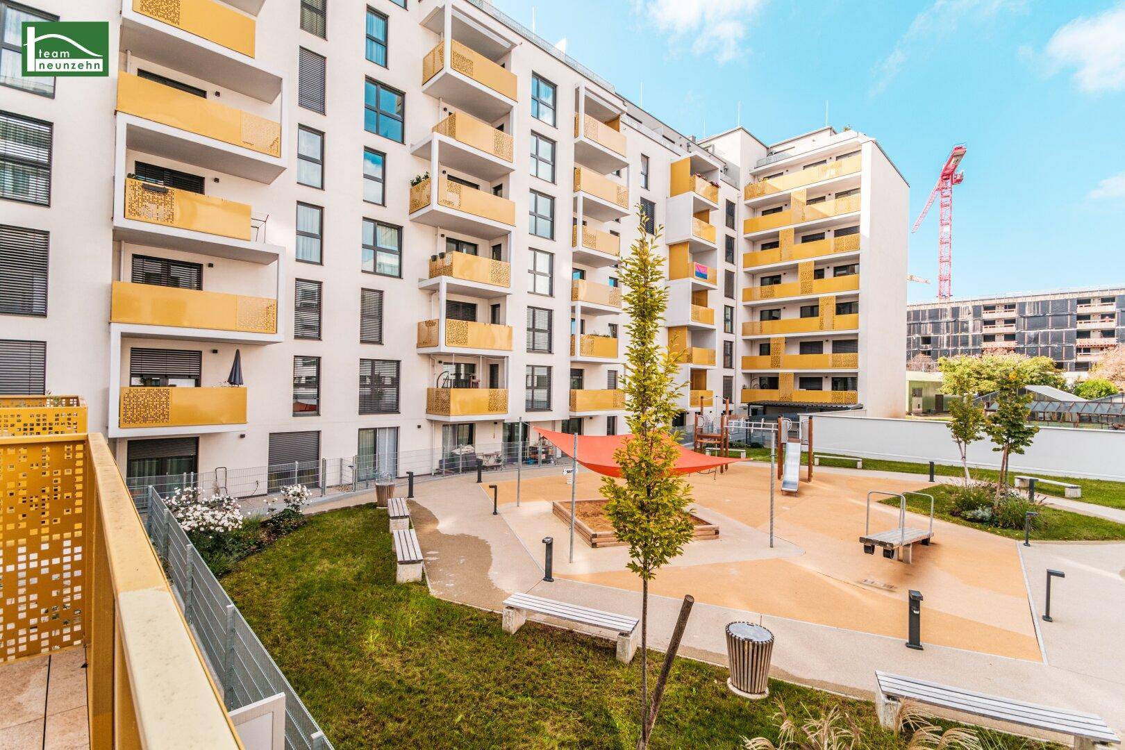 Gemeinschaftsgarten mit Spielplatz und Sitzgelegenheiten, umgeben von modernen Wohngebäuden.
