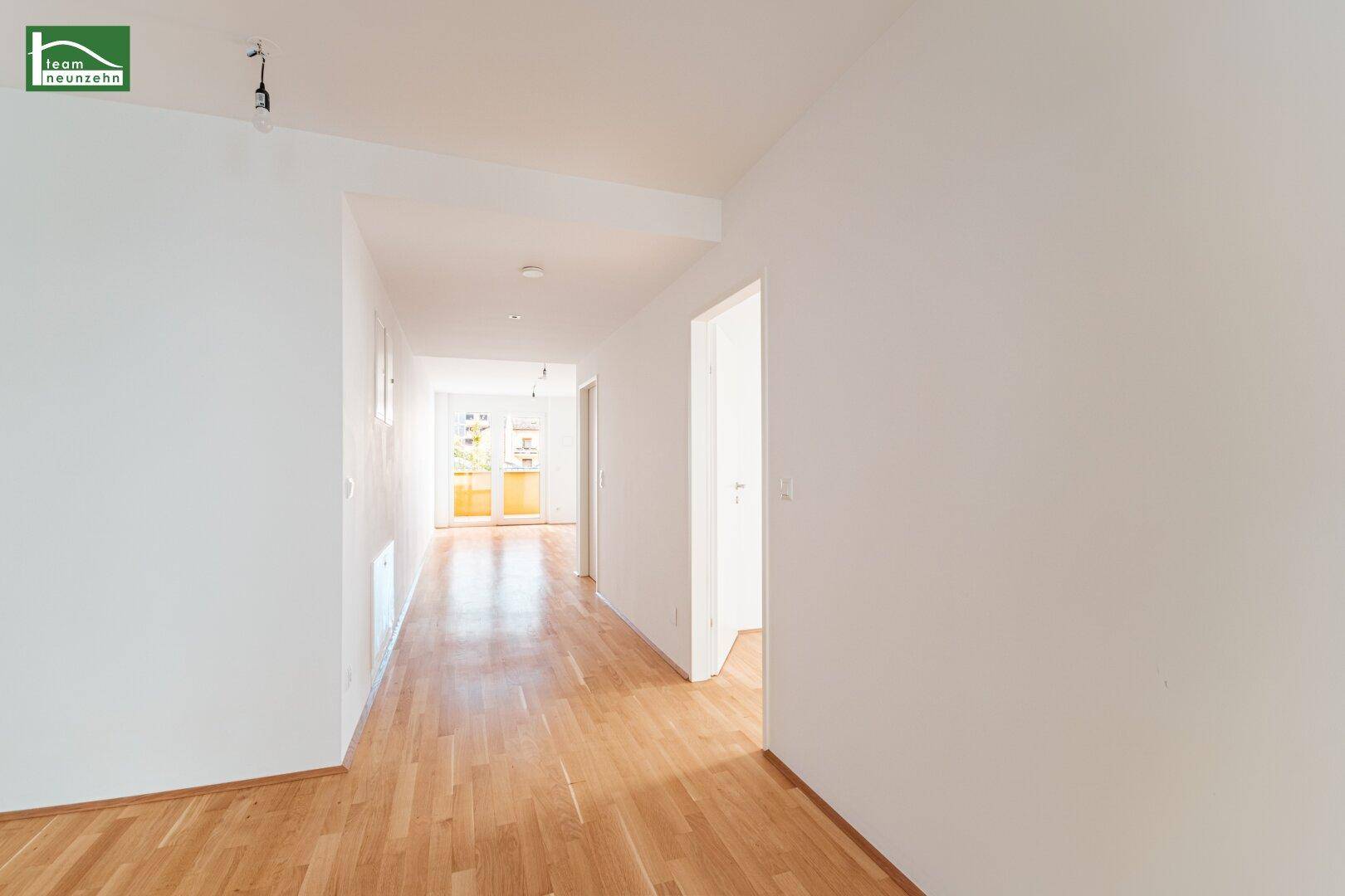 Langer, heller Flur mit Holzboden, der zu weiteren Räumen in der Wohnung führt.