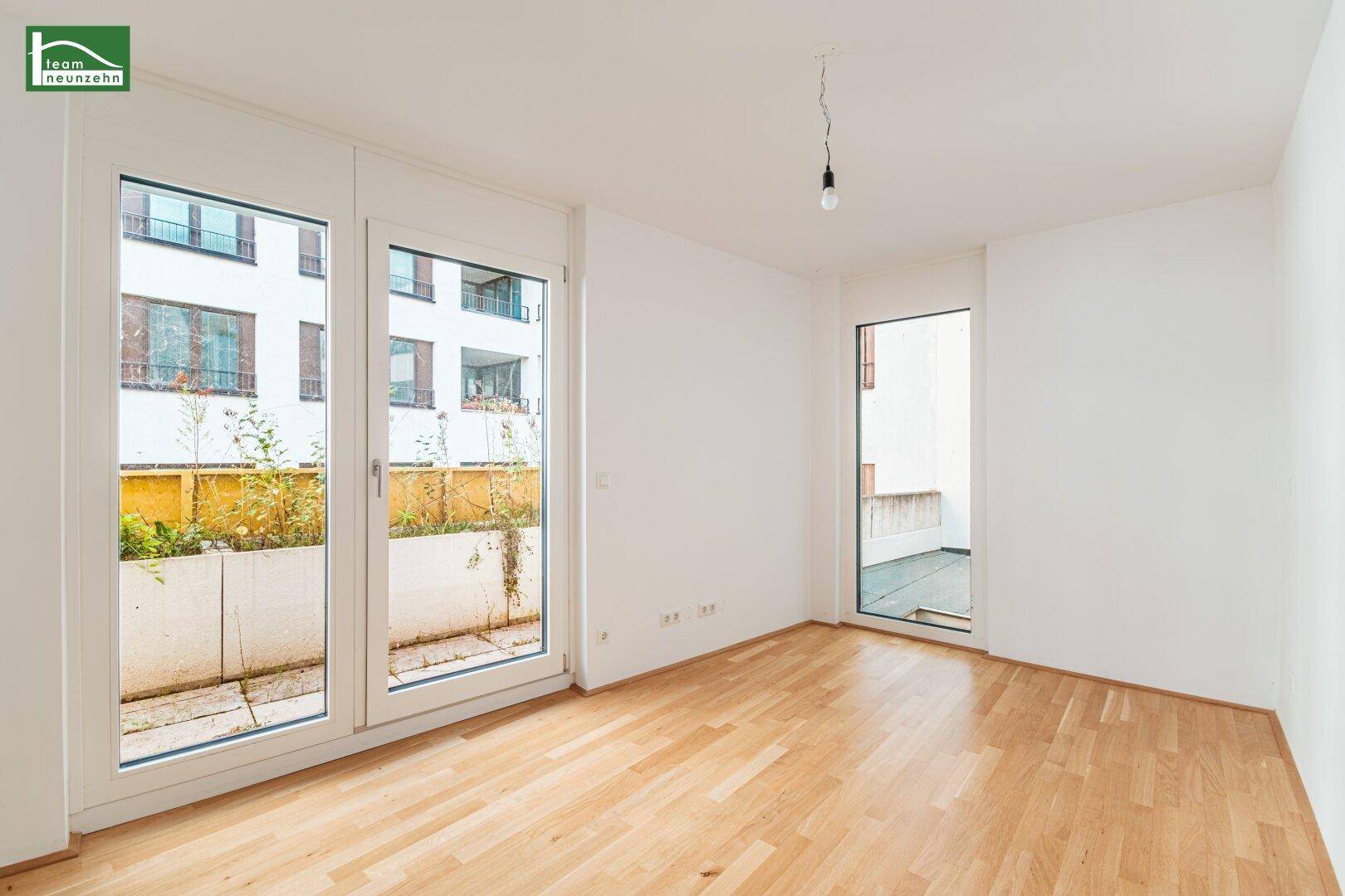Helles Zimmer mit Parkettboden und Zugang zu einem privaten Außenbereich.