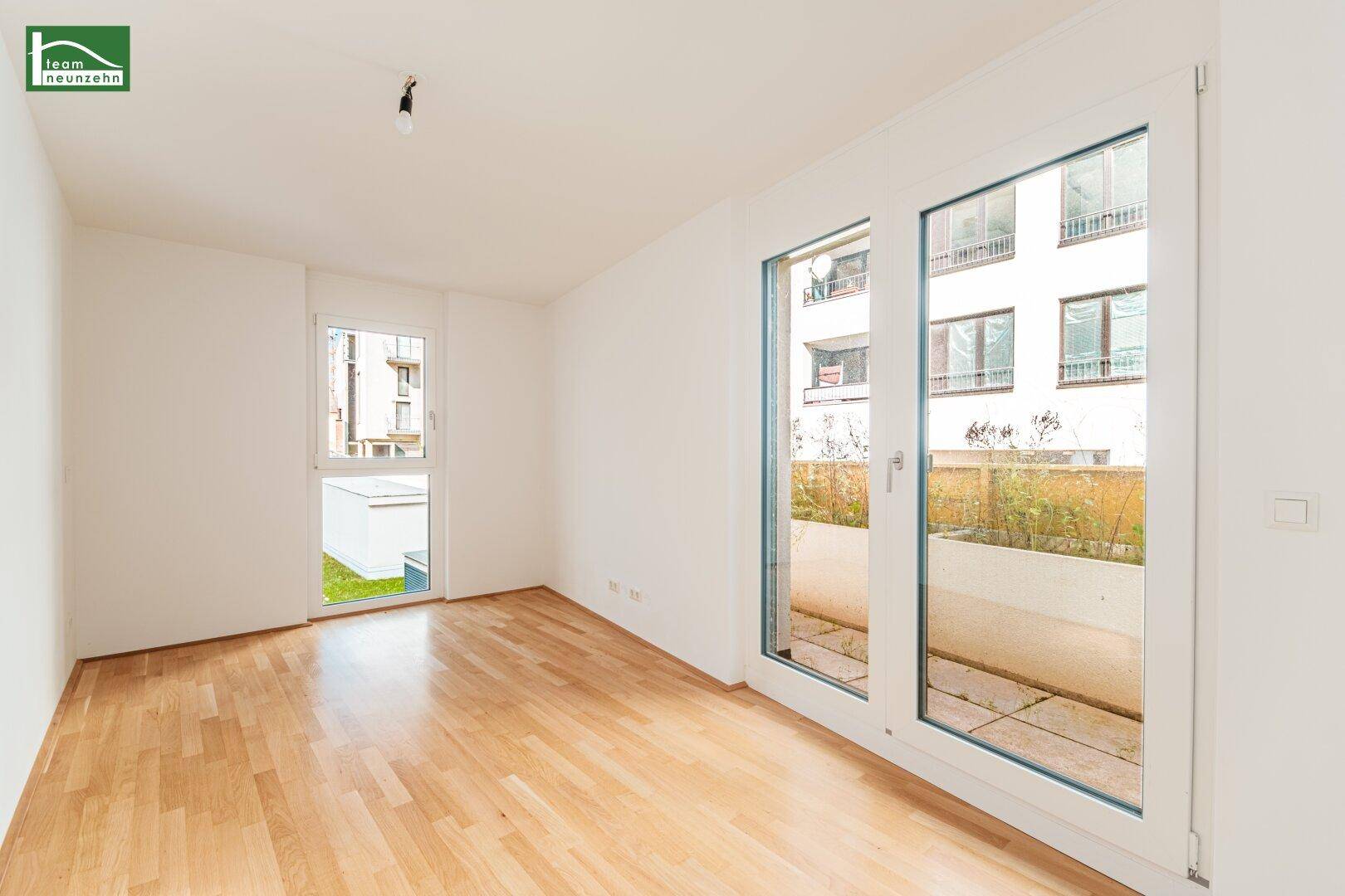 Helles Schlafzimmer mit Parkettboden und Zugang zu einem kleinen Gartenbereich.
