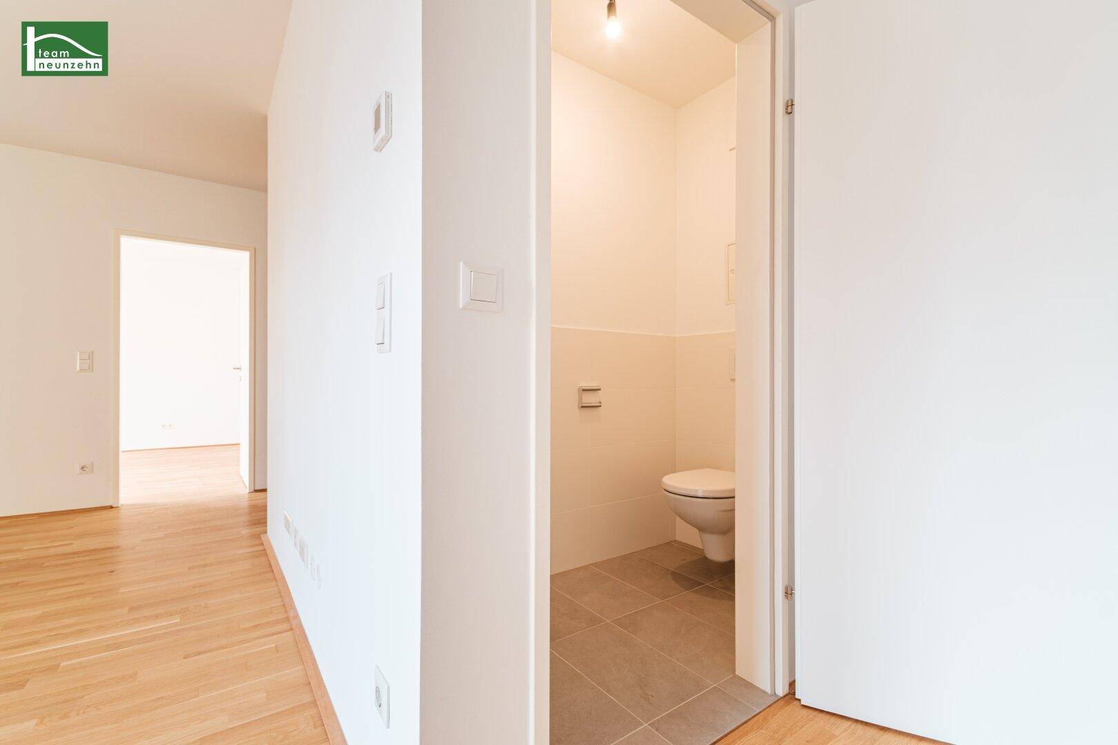 Heller Flur mit Parkettboden und Blick in eine separate, moderne Gästetoilette.
