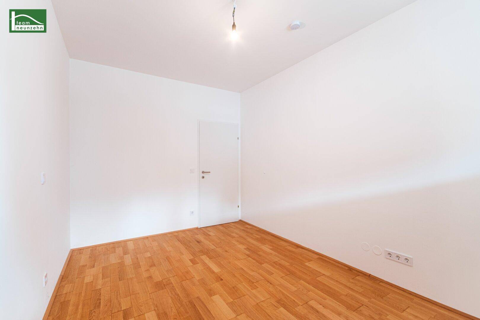 Leeres Zimmer mit Parkettboden und weiß gestrichenen Wänden, ideal als Schlaf- oder Arbeitszimmer.
