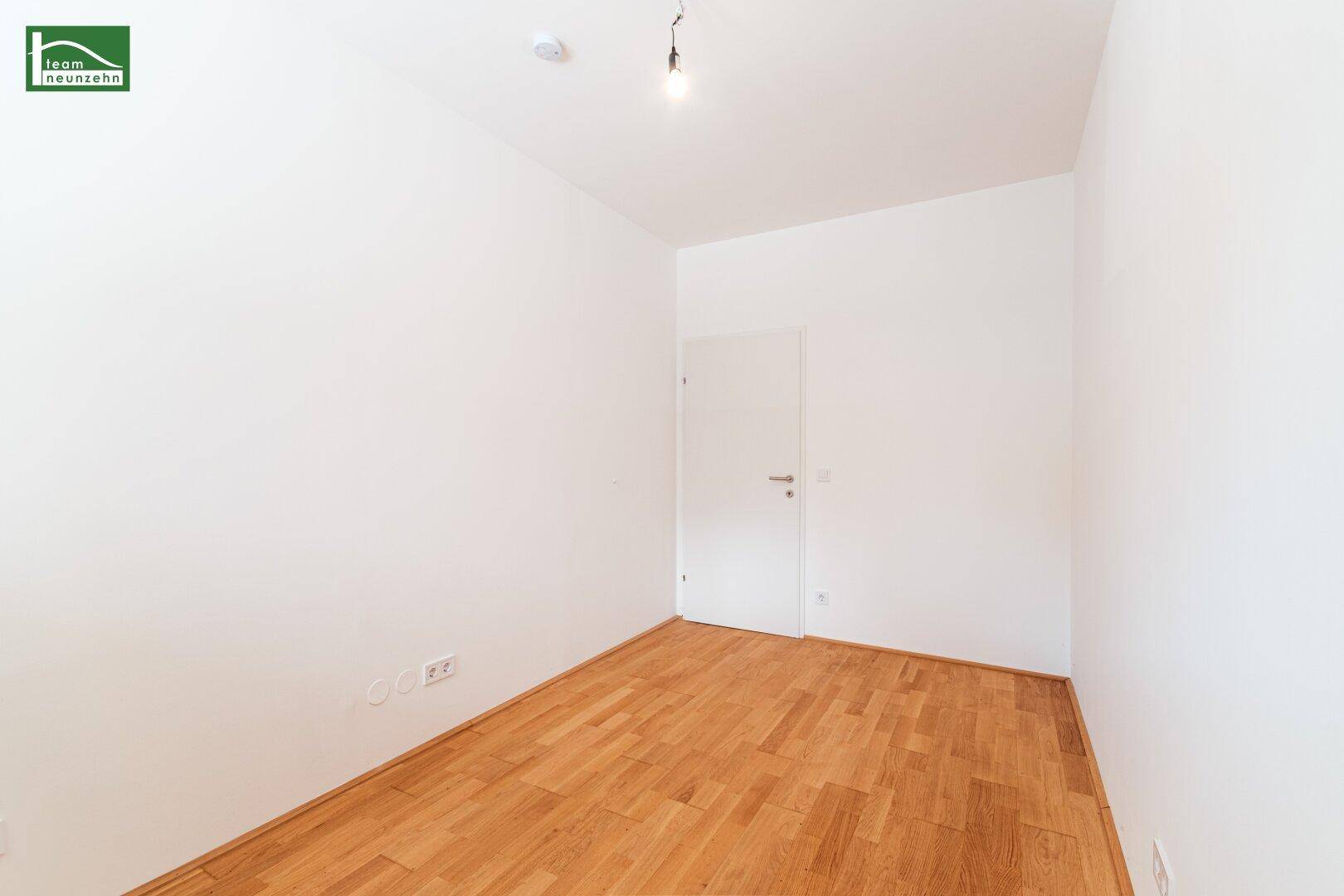 Leeres Zimmer mit Parkettboden und weiß gestrichenen Wänden, bereit zur individuellen Gestaltung.