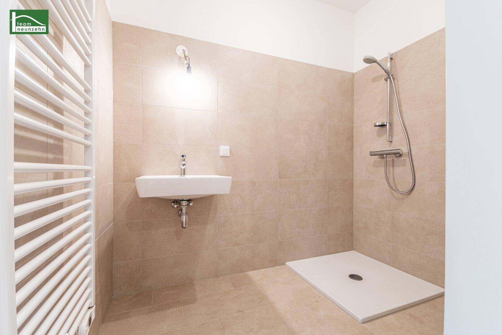 Modernes Badezimmer mit begehbarer Dusche, beigefarbenen Fliesen und Handtuchheizkörper.