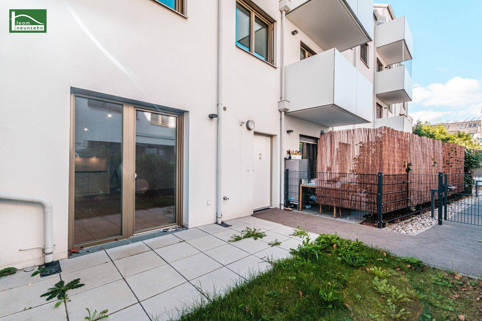 Gepflasterte Terrasse mit Sichtschutz und Zugang zu einer modernen Wohneinheit.