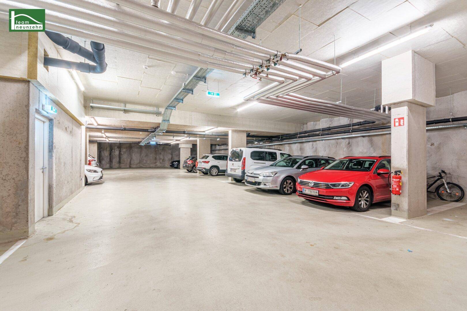 Geräumige Tiefgarage mit mehreren Stellplätzen und sichtbaren Versorgungsleitungen.