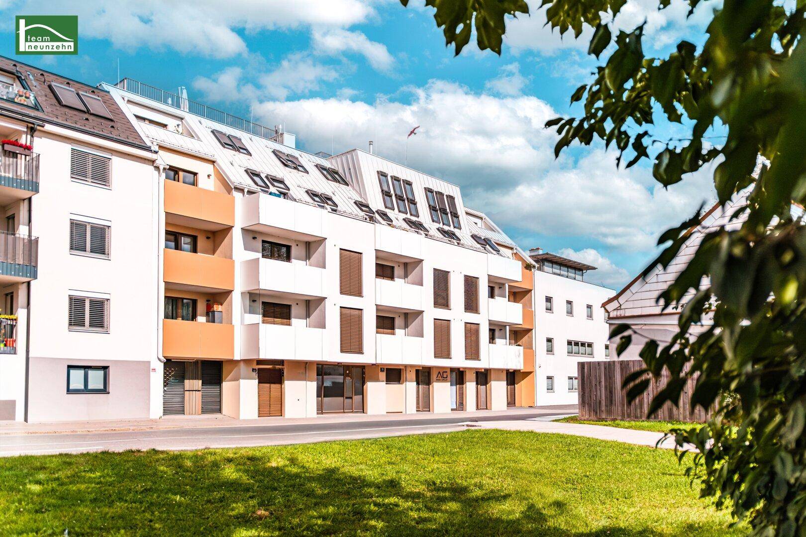 Moderne Wohnanlage mit weißer und beiger Fassade, Balkonen und Grünflächen.