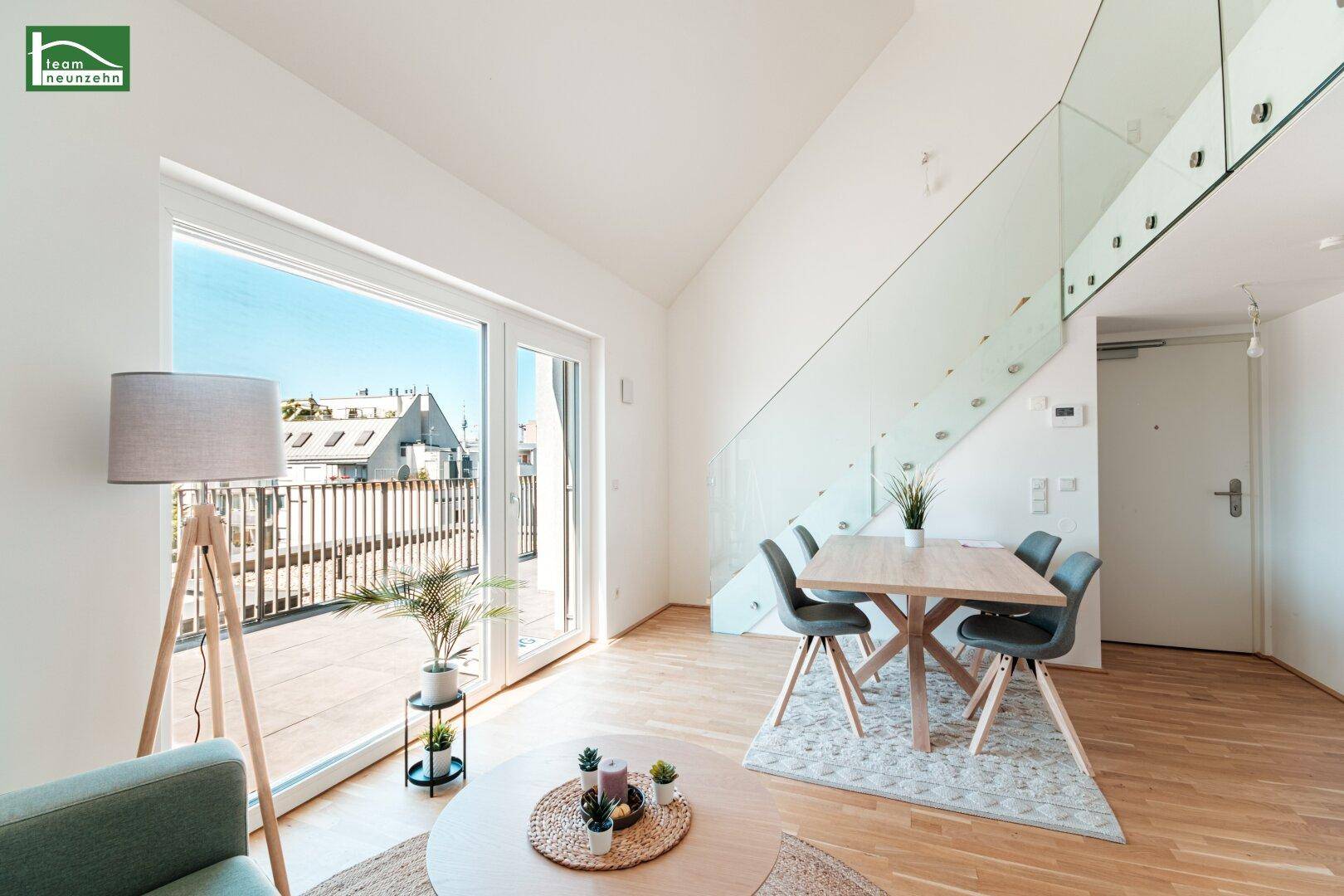Heller Wohn-Essbereich mit Holzboden, Zugang zur Terrasse und moderner Glasbrüstung der Treppe.