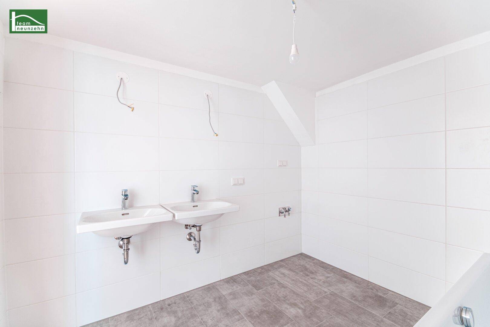 Modernes Badezimmer mit Doppelwaschbecken, weißen Fliesen und grauen Bodenfliesen, bereit für die Endmontage.