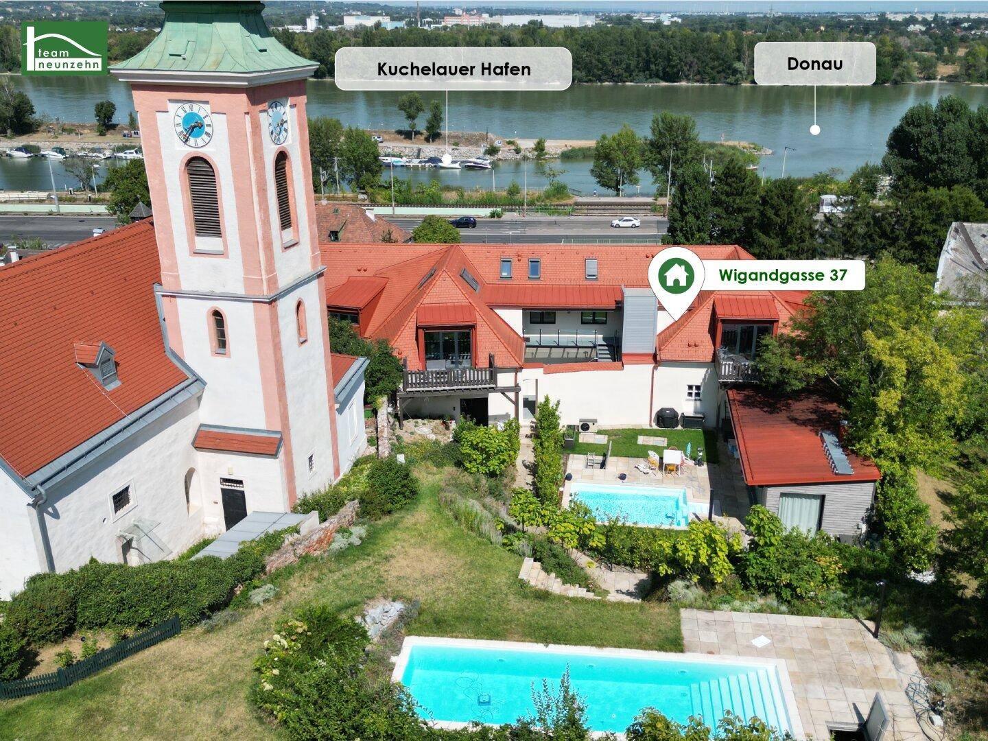 Luftaufnahme des Anwesens mit Kirche, Pools und Blick auf den Kuchelauer Hafen und die Donau.