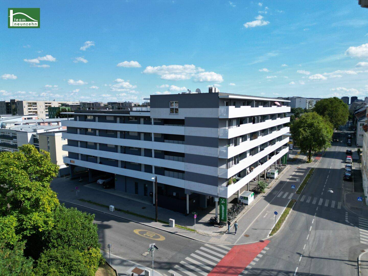 Moderne Wohnanlage mit mehreren Etagen und Balkonen in städtischer Umgebung.