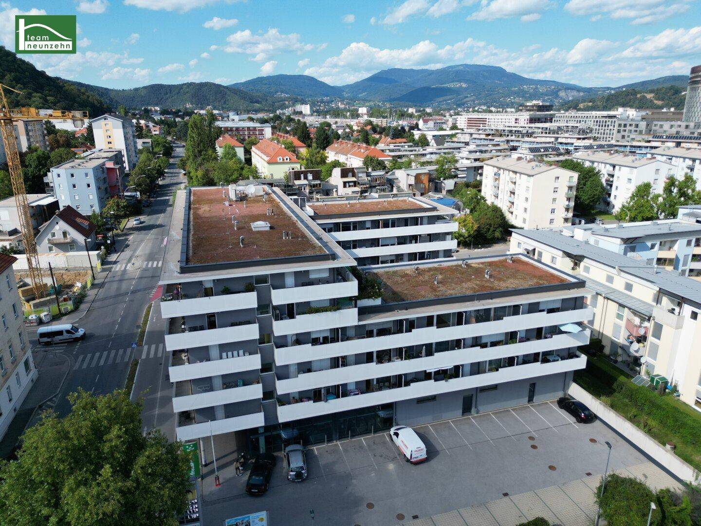 Luftaufnahme der modernen Wohnanlage mit Flachdach und umliegender Bebauung.