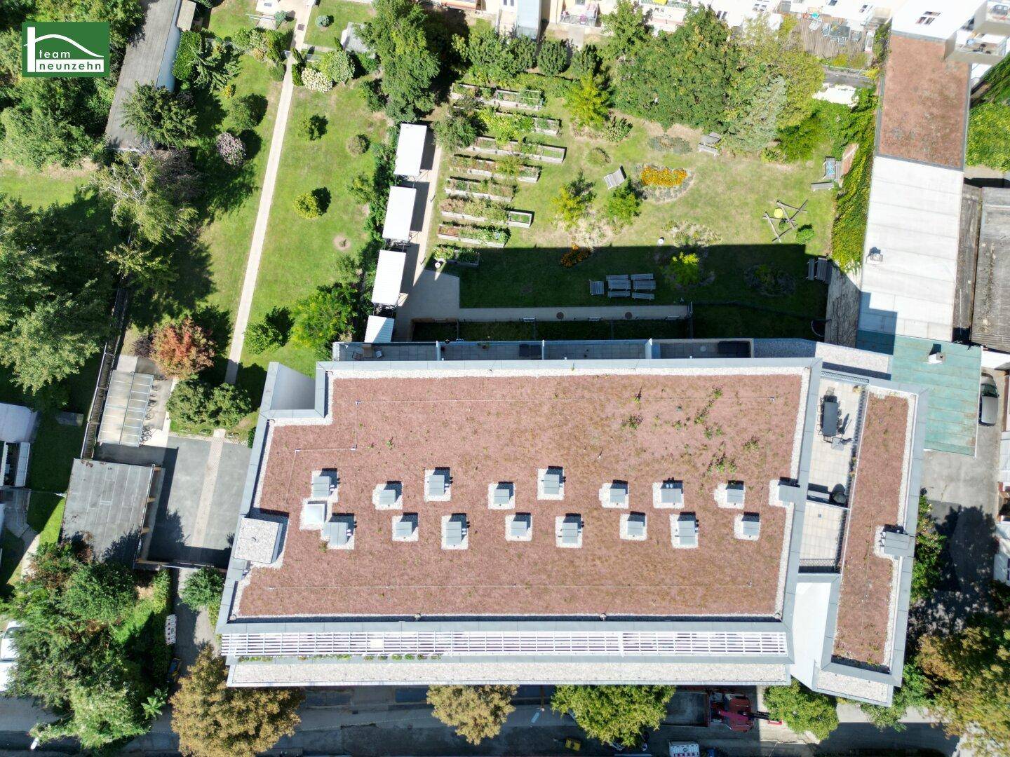 Draufsicht auf das Wohngebäude mit extensivem Gründach und angrenzenden Gärten und Grünflächen.