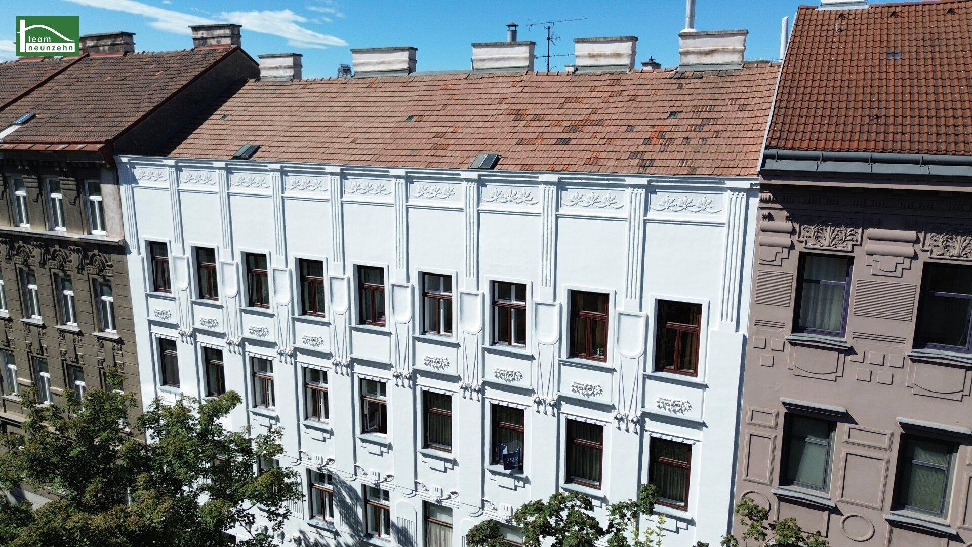 Luftaufnahme der Gebäudefassade mit Ziegeldach und umliegenden Altbauten.