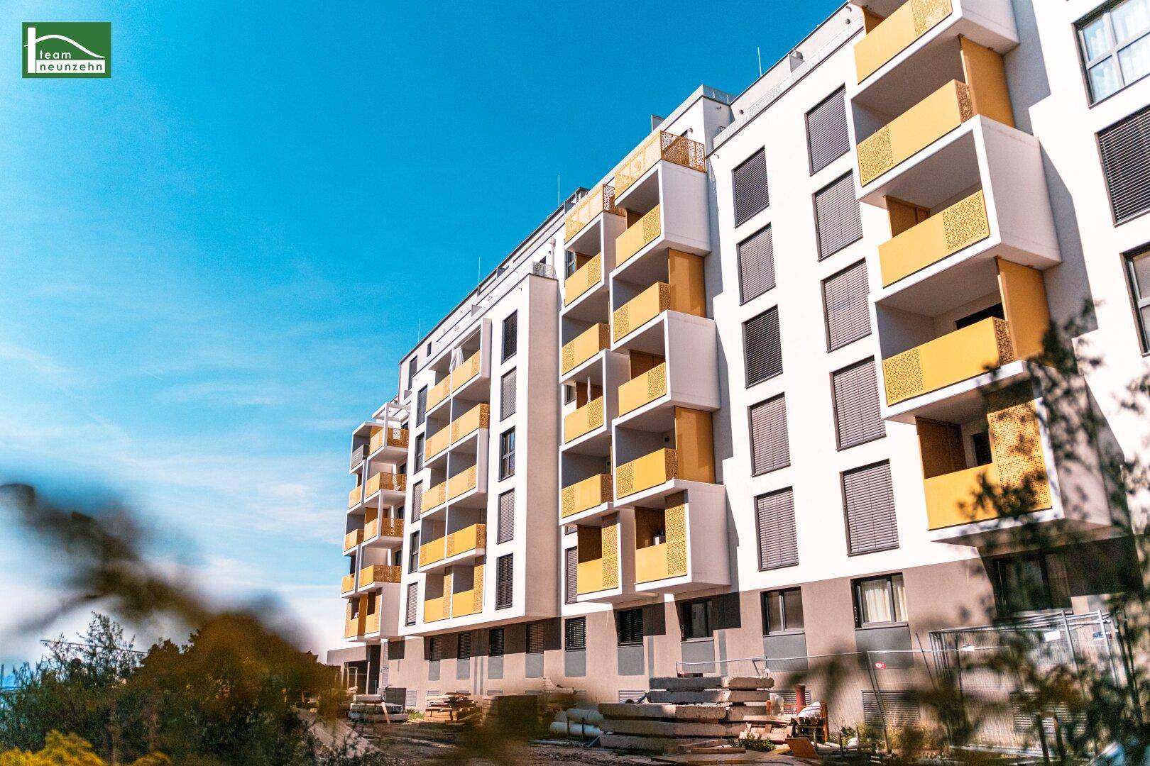 Moderne Wohngebäude mit markanten gelben Balkonen unter blauem Himmel.