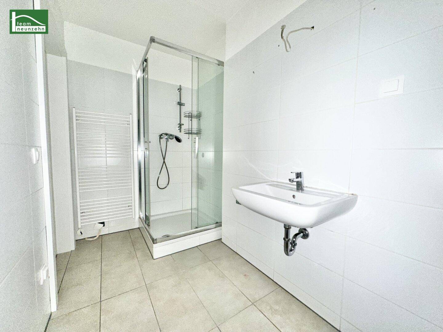 Modernes Badezimmer mit weiß gefliesten Wänden, Duschkabine und Handtuchheizkörper.