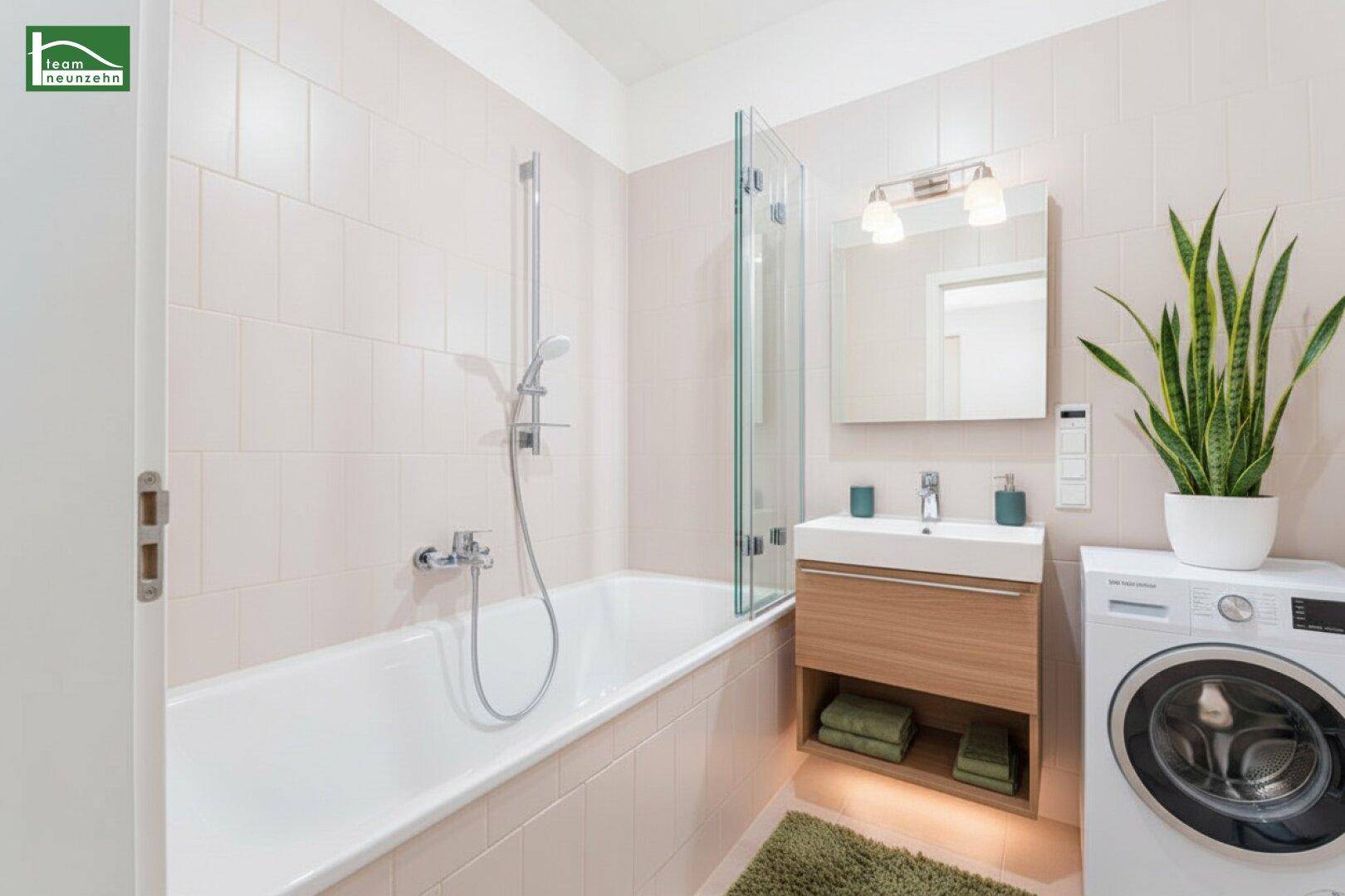 Modernes Badezimmer mit Badewanne, Waschbeckenunterschrank und Waschmaschine, hell gefliest.