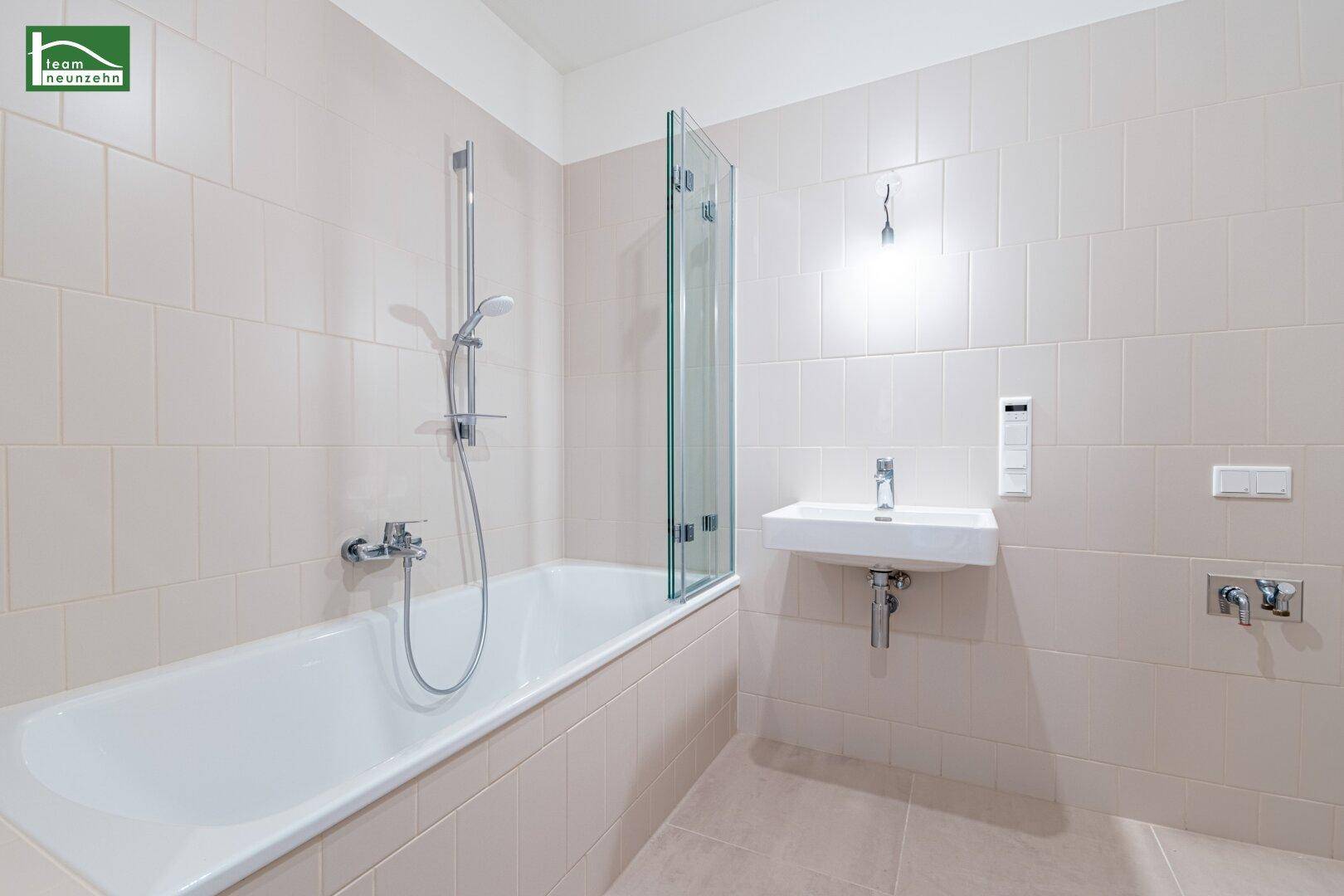 Modernes Badezimmer mit Badewanne, Duschabtrennung und hellem Fliesenboden.