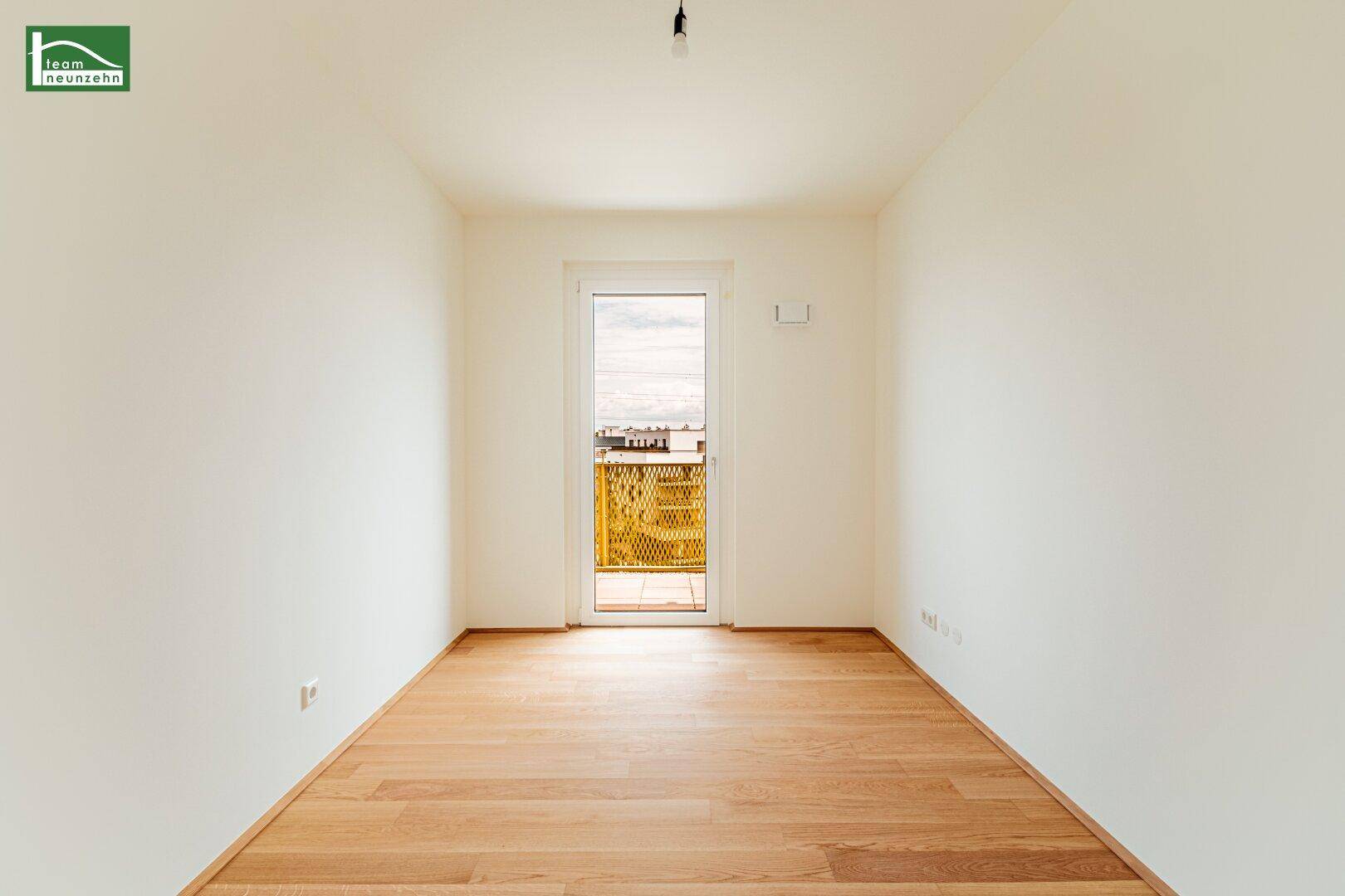 Geräumiges Schlafzimmer mit Holzboden und Balkonzugang, lichtdurchflutet.