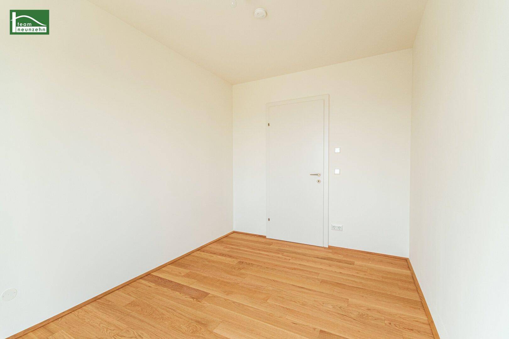 Leeres Schlafzimmer mit Holzboden und weißer Tür, bietet viel Gestaltungspotenzial.