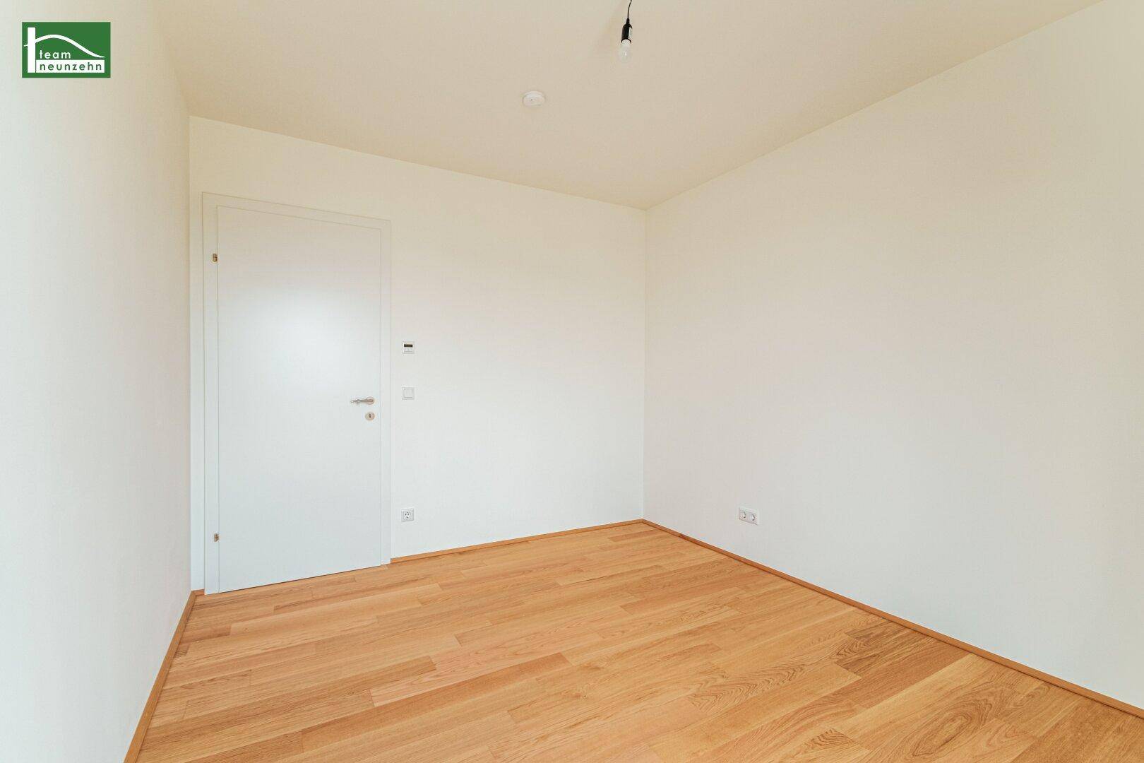 Leeres Schlafzimmer mit Holzboden und weißer Tür, ideal für individuelle Gestaltung.