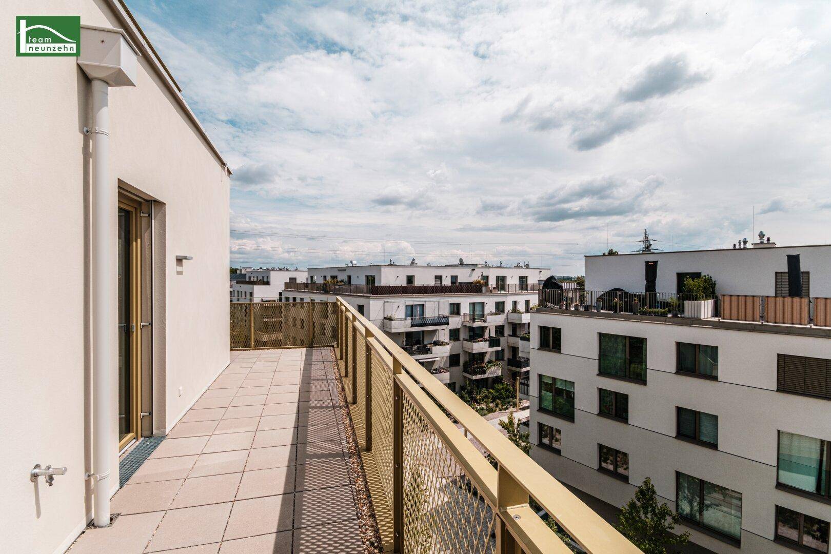 Breiter Balkon mit Fliesenboden und Blick auf die umliegenden Wohngebäude.