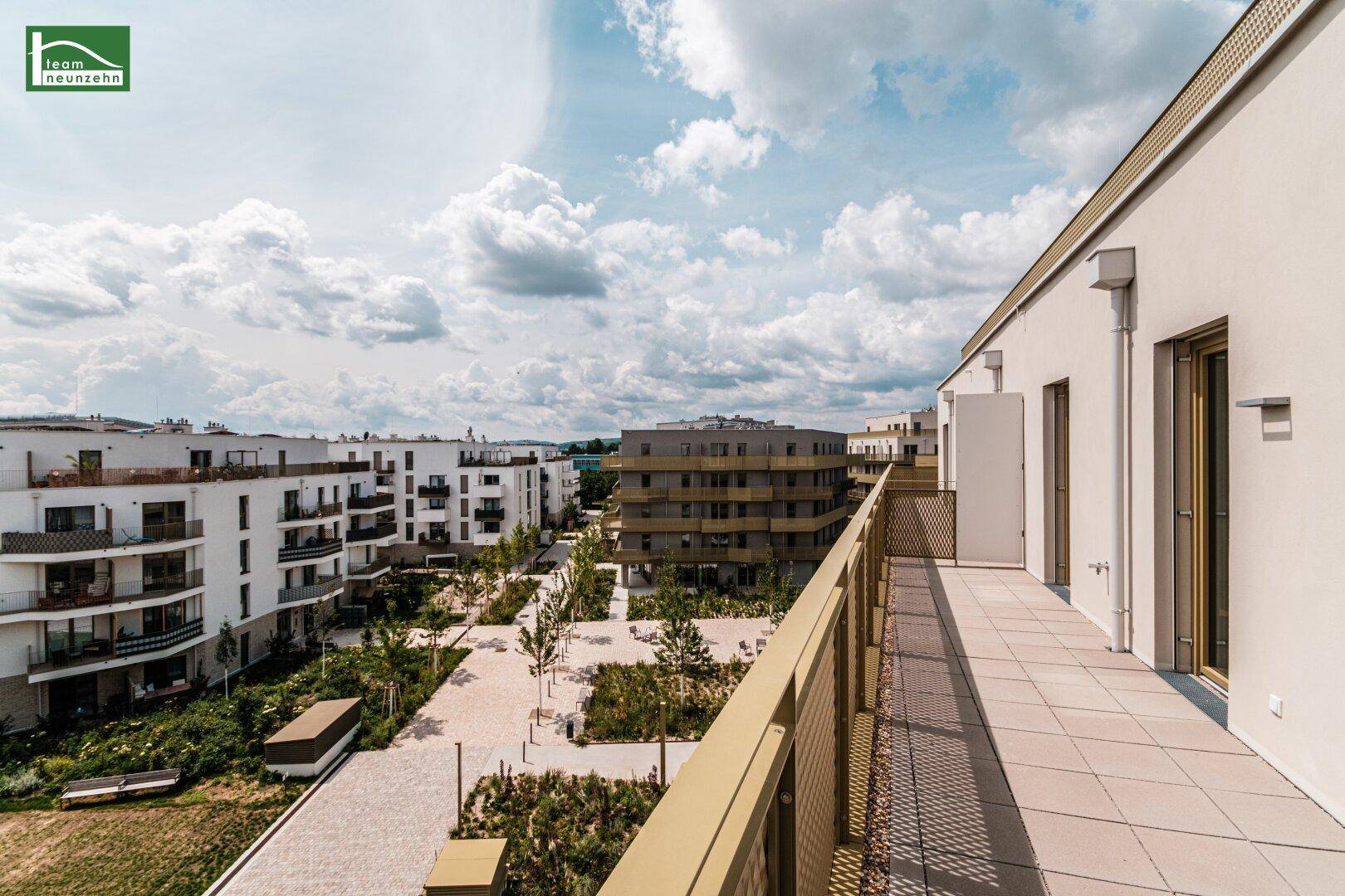 Langer Balkon mit Fliesenboden und weitem Blick über die moderne Wohnanlage.