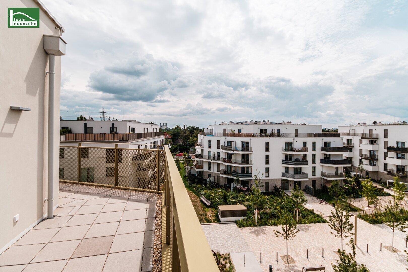 Weitläufige Dachterrasse mit Blick auf die moderne Wohnanlage und den Himmel.