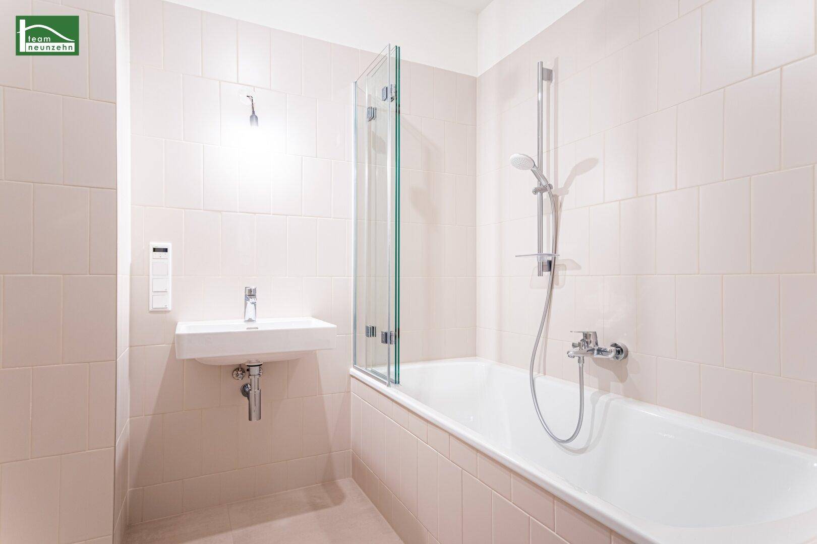 Modernes Badezimmer mit Badewanne, Duschabtrennung und hellem Fliesenboden.