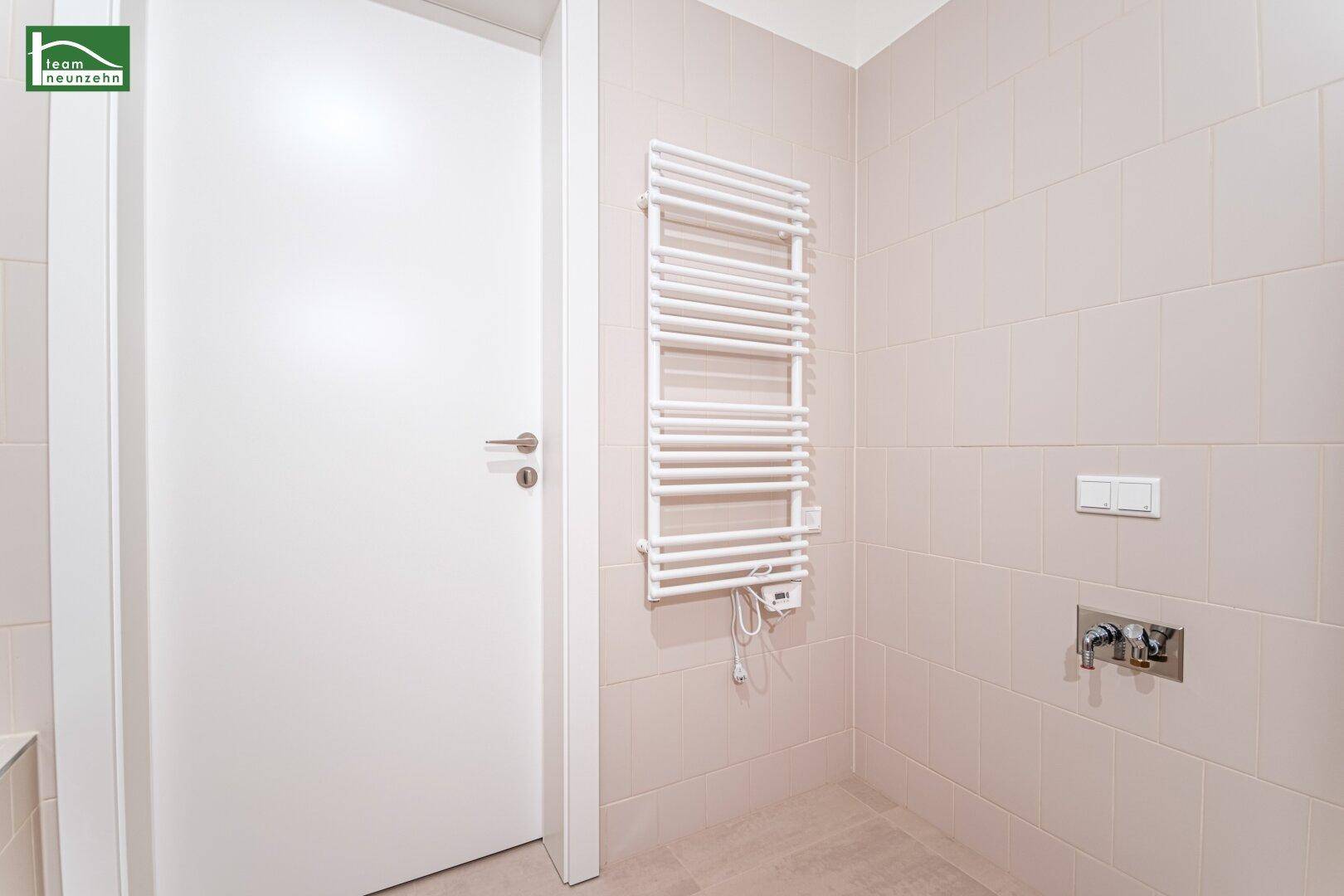 Badezimmer mit weißem Handtuchheizkörper und hellen Fliesen, bereit für die Installation.