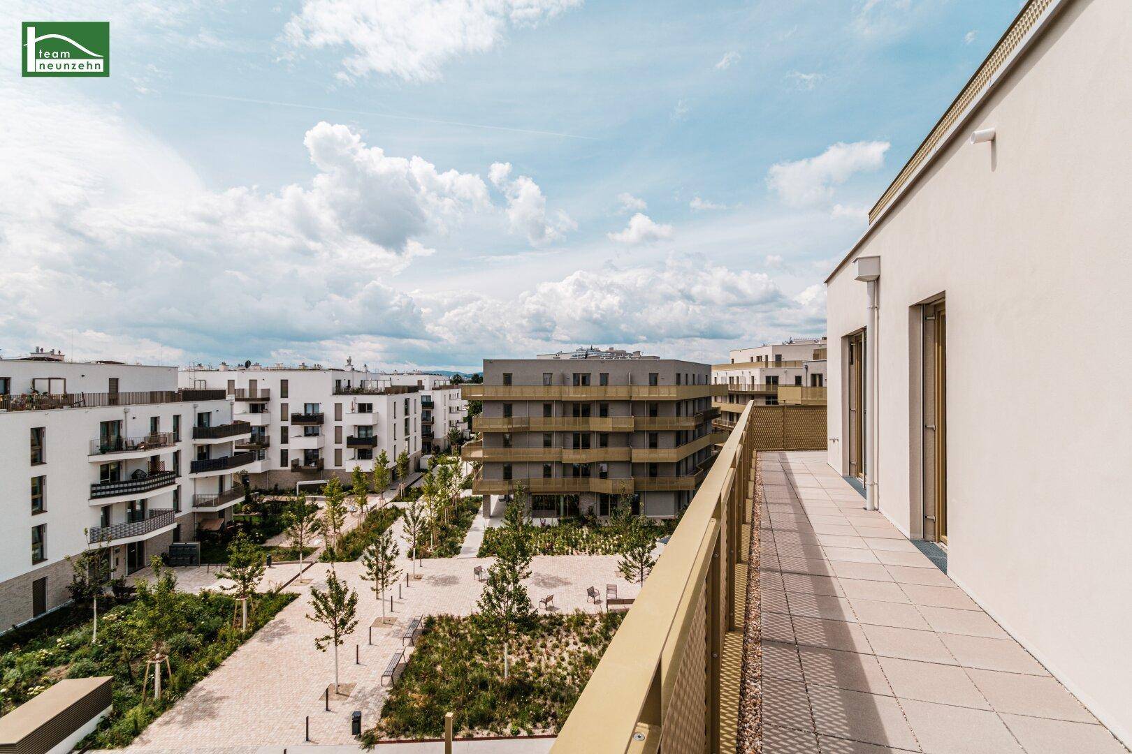 Große Dachterrasse mit Blick auf die umliegenden Neubauten und Grünflächen.