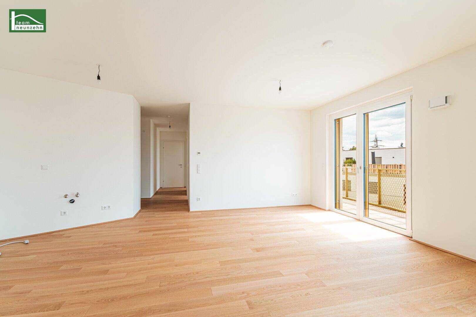 Offener Wohnbereich mit Holzboden und großen Schiebetüren zum Außenbereich.