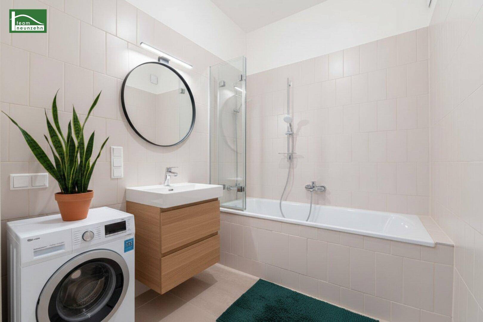 Funktionales Badezimmer mit Badewanne, Waschbeckenunterschrank und Waschmaschine, hell gefliest.