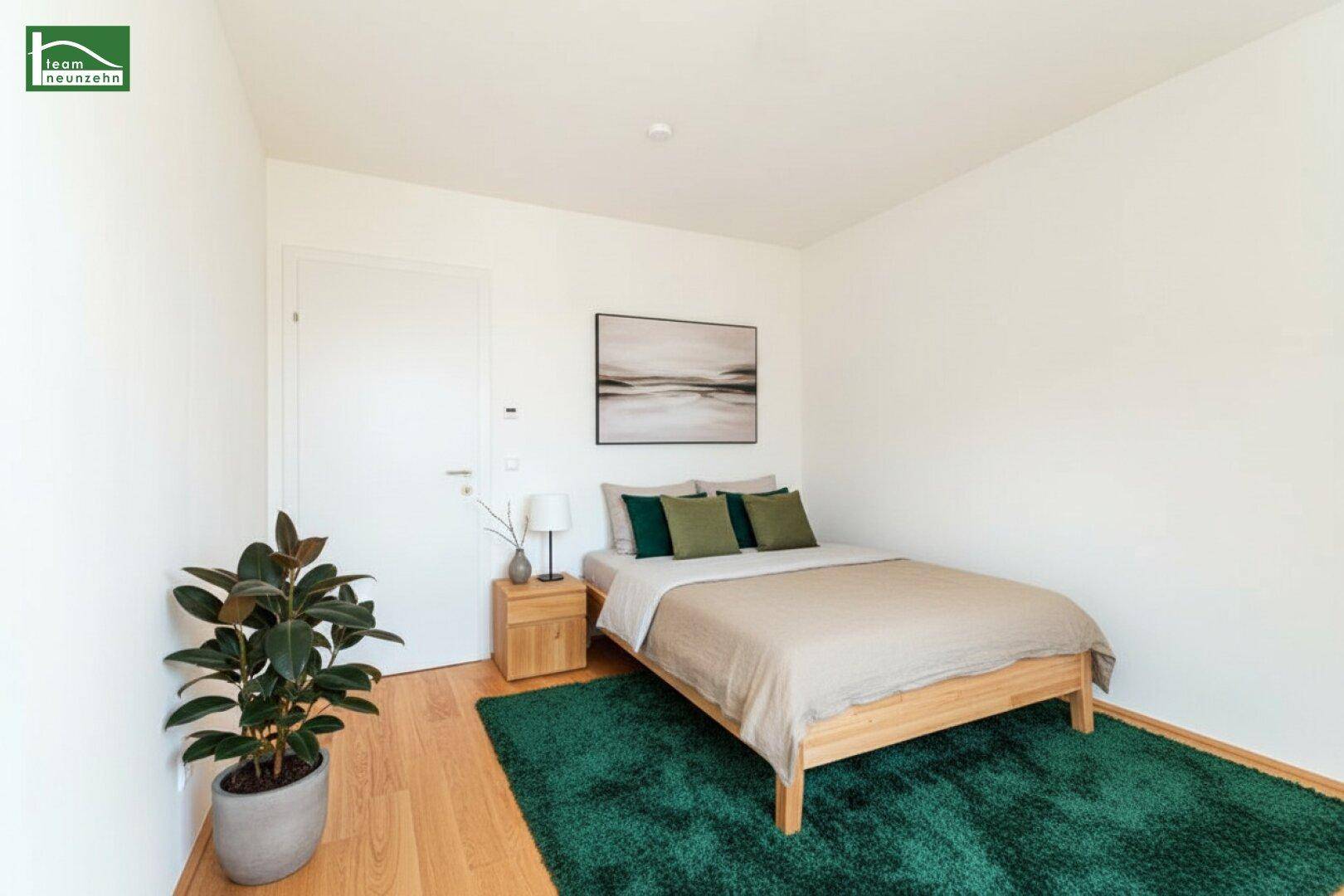 Gemütliches Schlafzimmer mit Holzboden, einem Doppelbett und einem grünen Teppich.