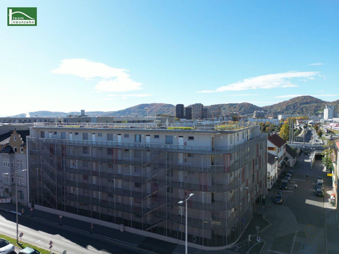 Weitläufige Luftaufnahme des Gebäudes mit Stadt- und Bergblick im Hintergrund.