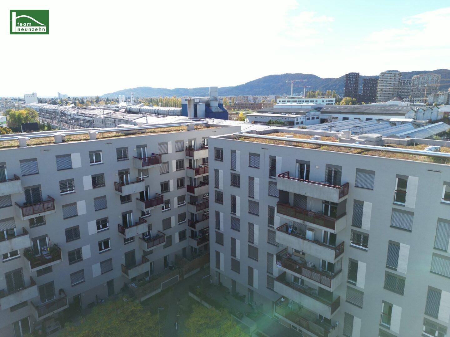 Luftaufnahme der Wohnanlage mit Blick auf die umliegende Stadt und Berge im Hintergrund.